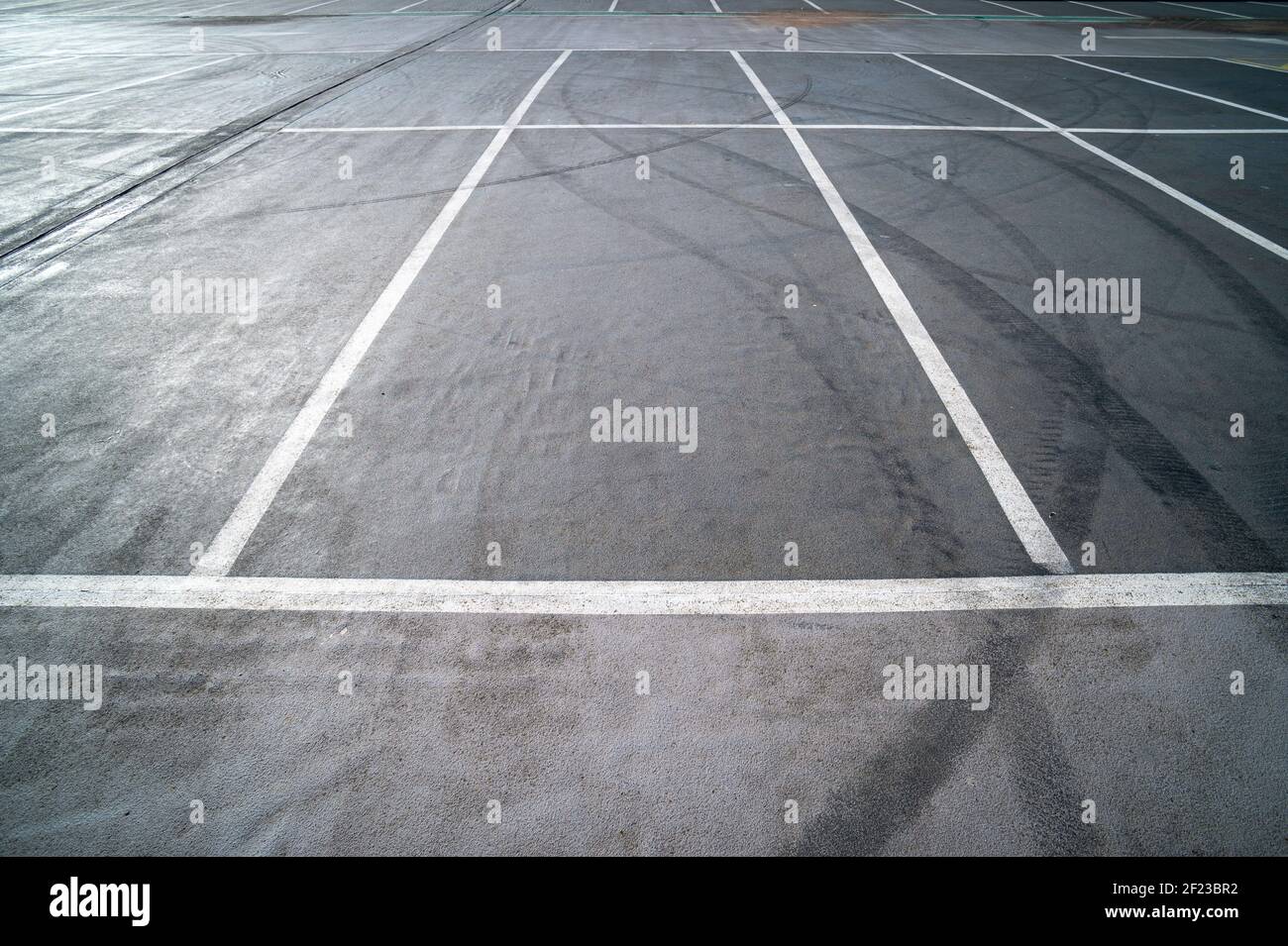 Les aires de stationnement vides sont dotées de lignes peintes en blanc et de marques de pneus noires. Banque D'Images