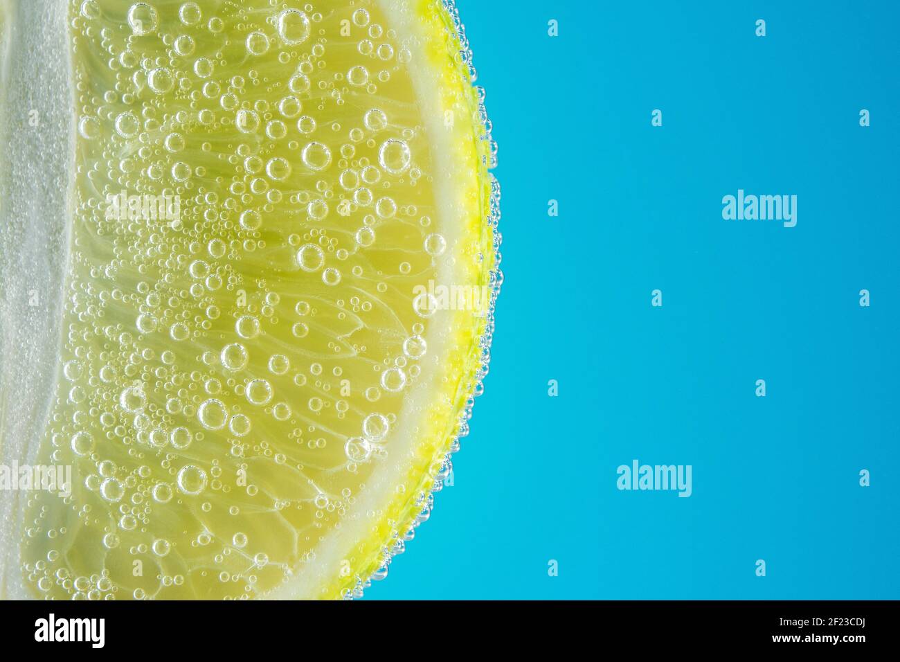 Vue rapprochée d'une tranche de chaux dans de l'eau sodée avec des bulles. Concept de boisson d'été. Banque D'Images