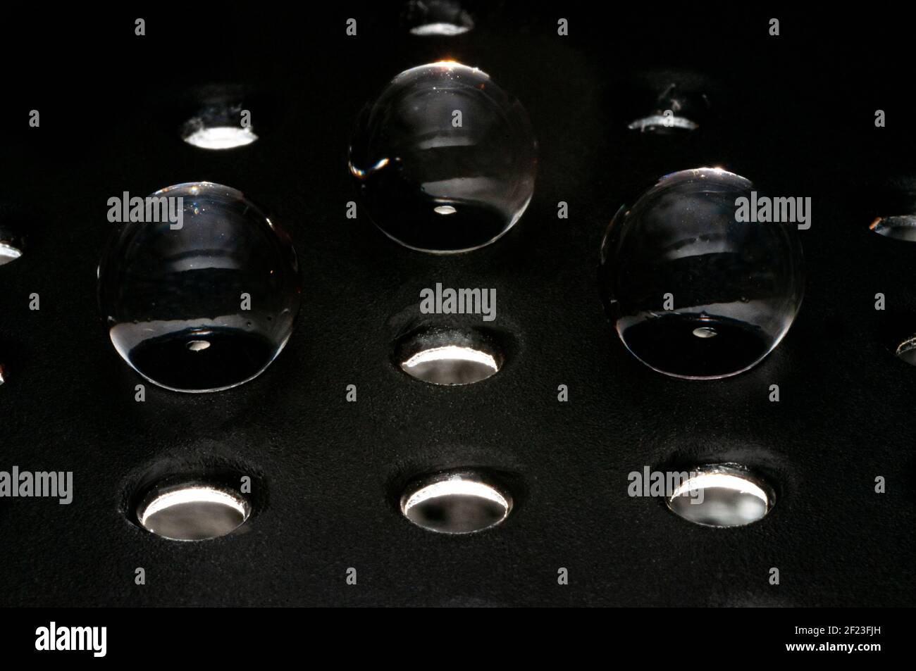 Trois sphères de verre dans le trou sur une grille métallique prise en charge sur fond noir Banque D'Images