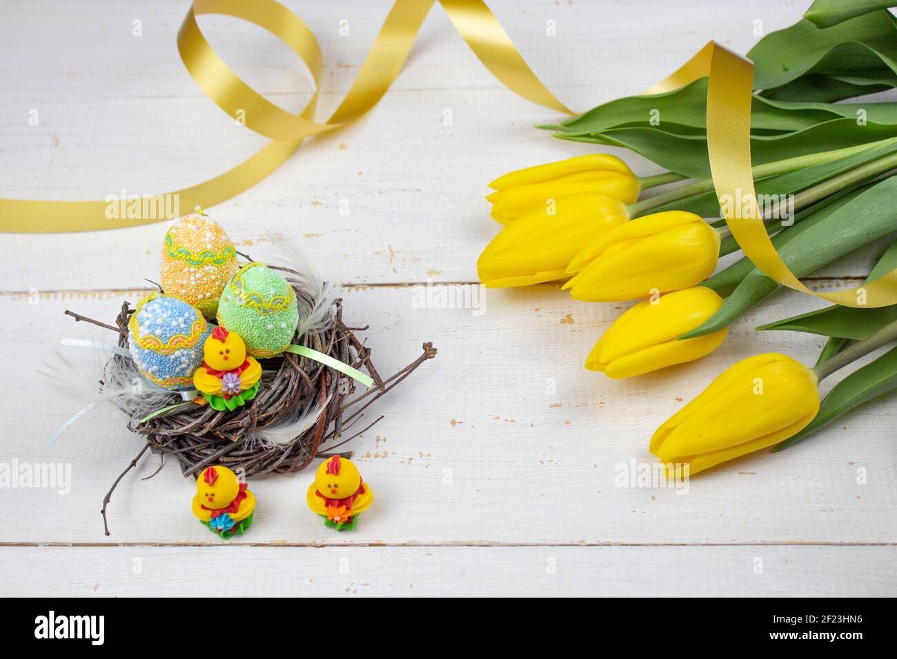 Œufs de Pâques. Bonne carte de Pâques. Œufs de Pâques multicolores. Pâques. Œufs de Pâques sur fond de bois blanc. Arrière-plan de Pâques. Tulipes jaunes Banque D'Images