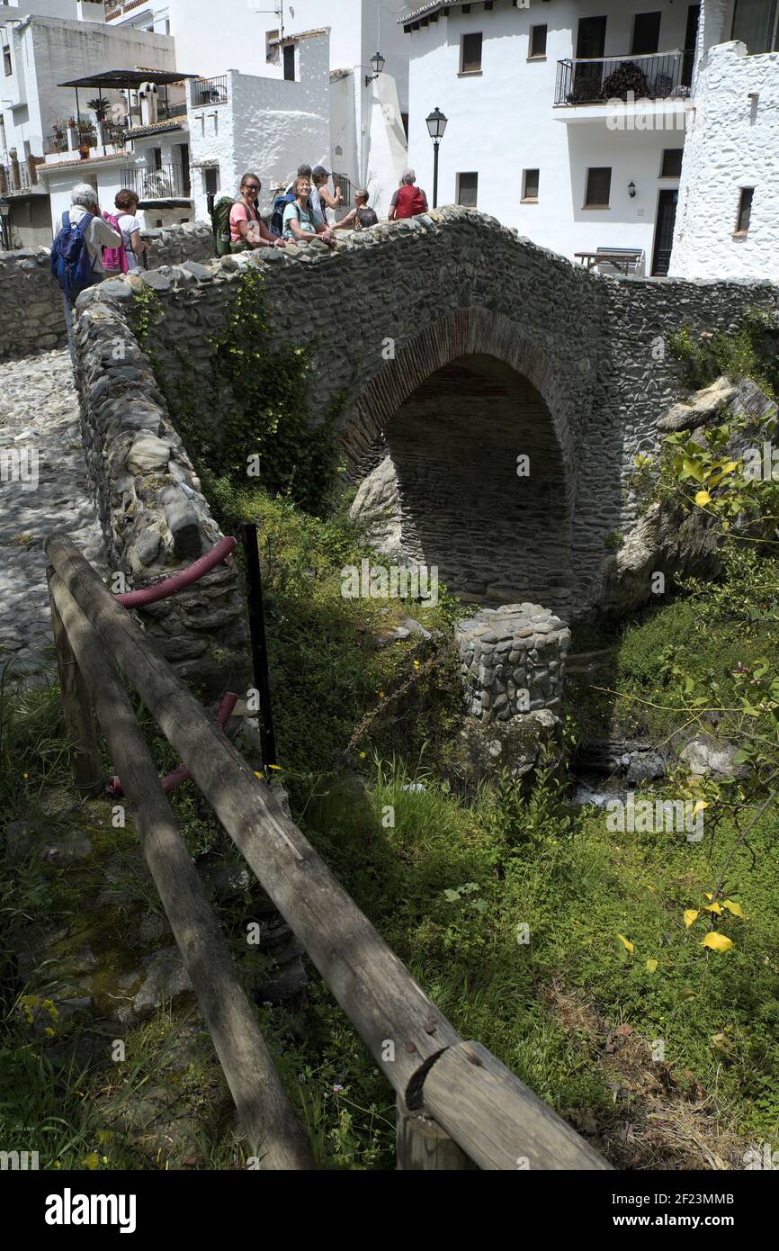 Touristes sur le vieux pont en arc de pierre romaine, Salares, Andalousie, Espagne. Banque D'Images