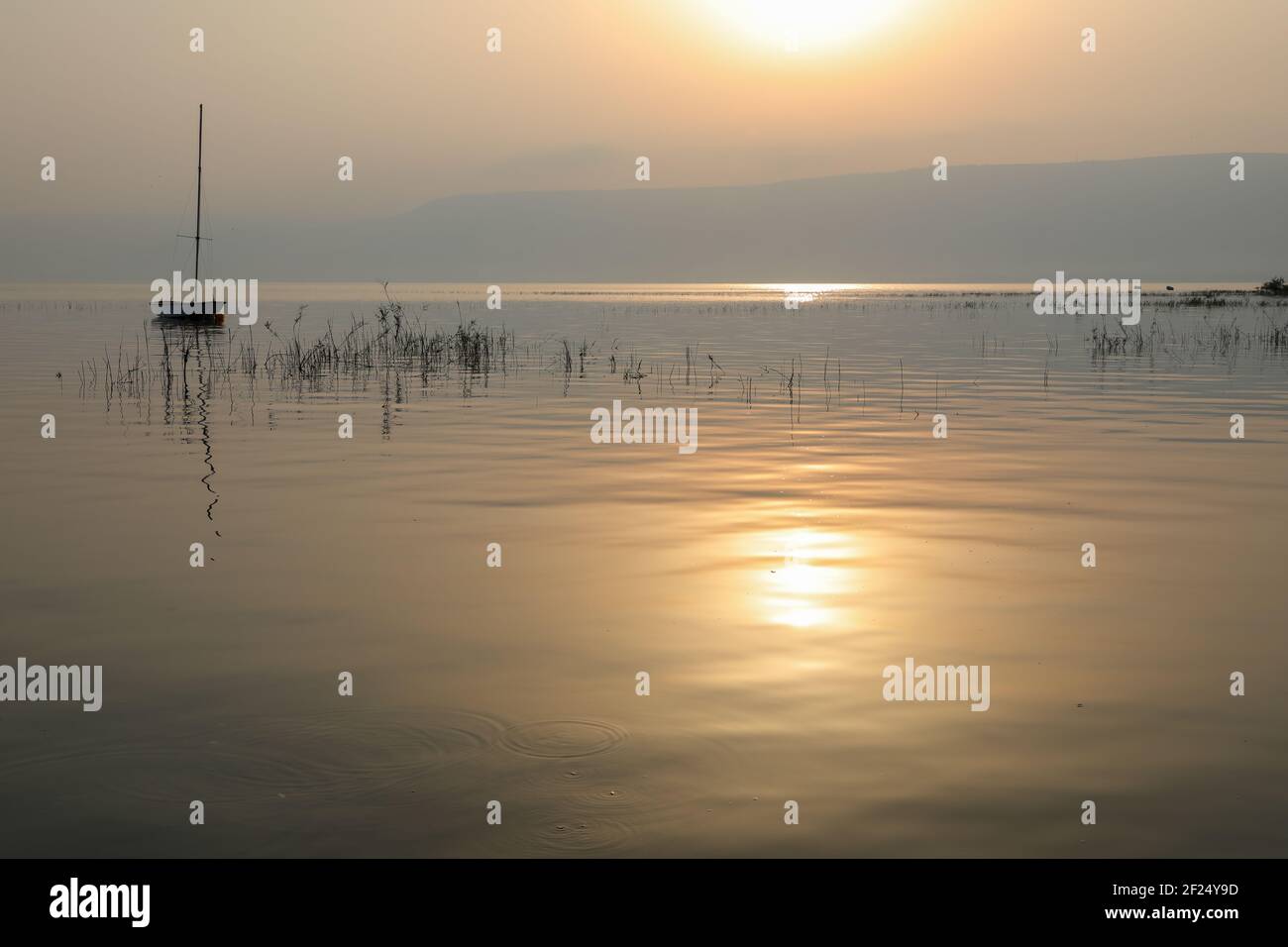 Lever du soleil sur le lac. Bateau flottant sur l'eau calme sous un coucher de soleil étonnant. Banque D'Images