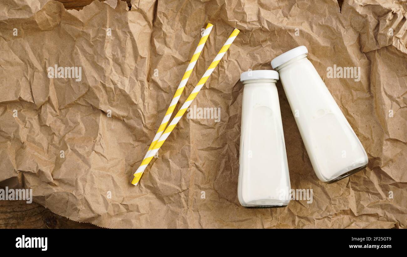Lait de vache biologique en bouteilles de verre. Deux bouteilles de lait sur papier artisanal froissé Banque D'Images
