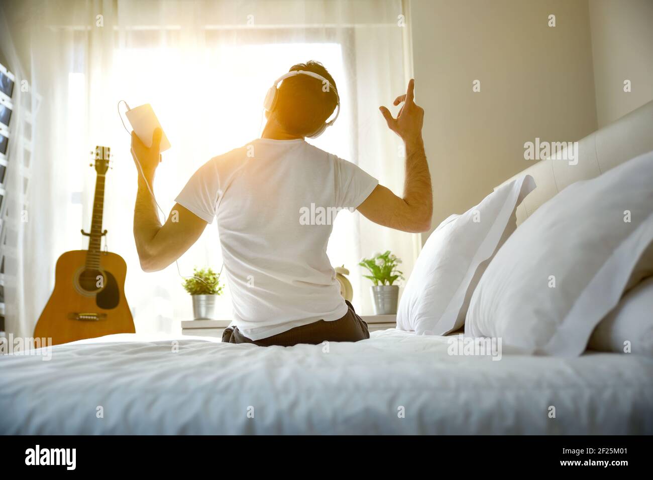 Je me suis réveillé le matin en écoutant de la musique sur le lit à  l'arrière avec une fenêtre dans l'arrière-plan entrant dans la lumière du  soleil Photo Stock - Alamy