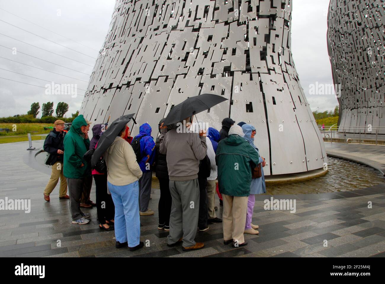 Groupe de personnes âgées visitant les Kelpies par une journée humide, The Helix, Falkirk, Écosse Banque D'Images