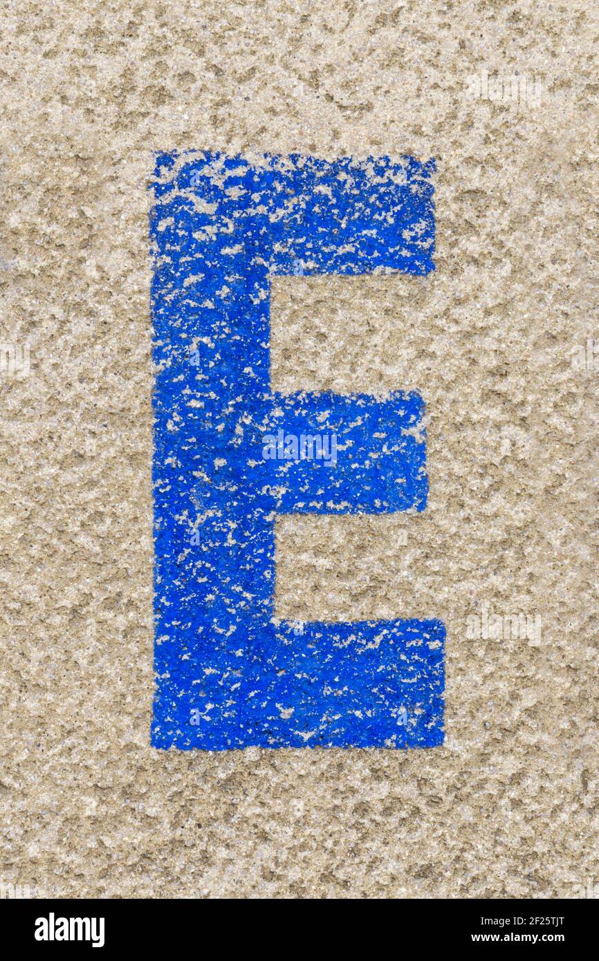 Lettre bleue E peinte sur un mur en plâtré de couleur bleue Banque D'Images