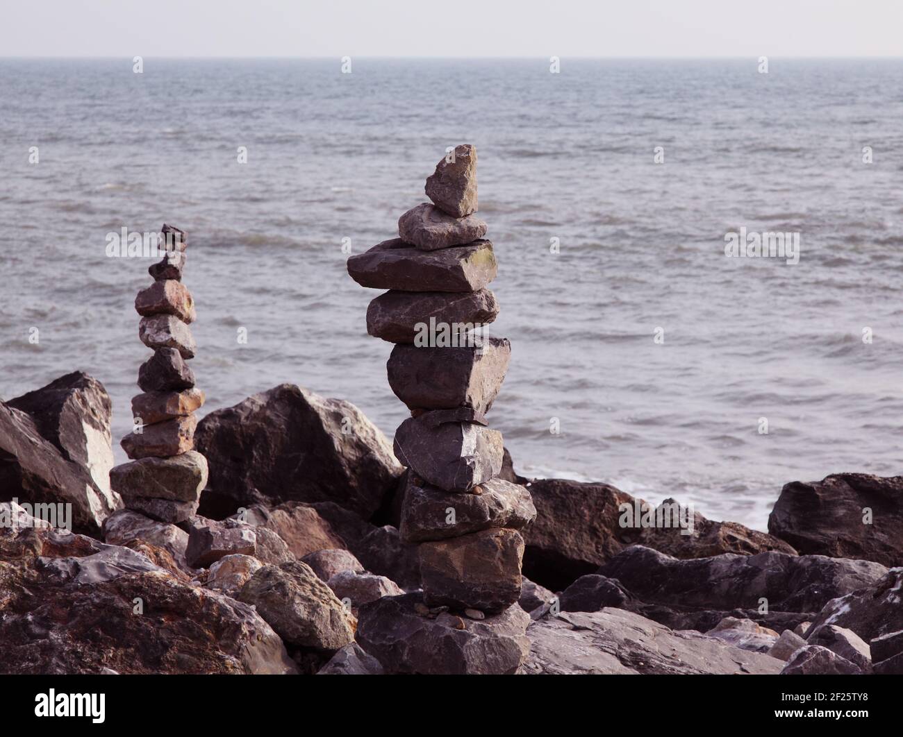 Pierres équilibrées ou pierres d'équilibrage. Empilé ou empilé pour faire de la pierre ou de la pierre de cairns sur le rivage de la plage avec la mer derrière. Banque D'Images