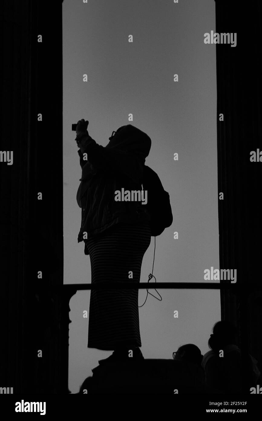 Portrait noir et blanc d'une femme prenant un photographie sur une corniche Banque D'Images