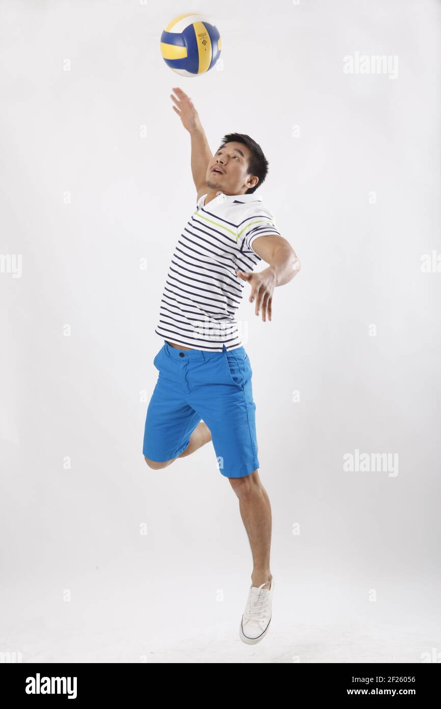 Un jeune homme jouant au volley-ball dans des vêtements décontractés Banque D'Images