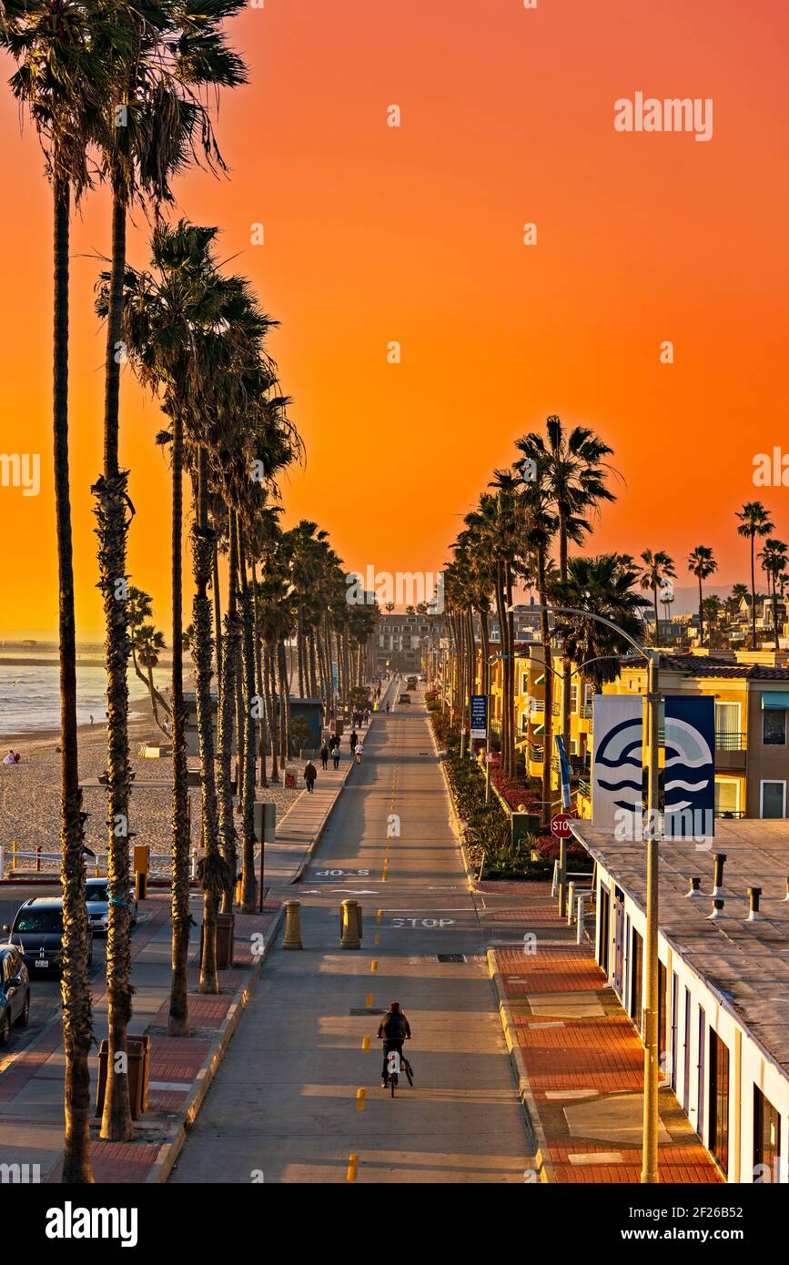 Coucher de soleil sur la rue avec les touristes et les entreprises le long de la plage, rue bordée de palmiers. Banque D'Images