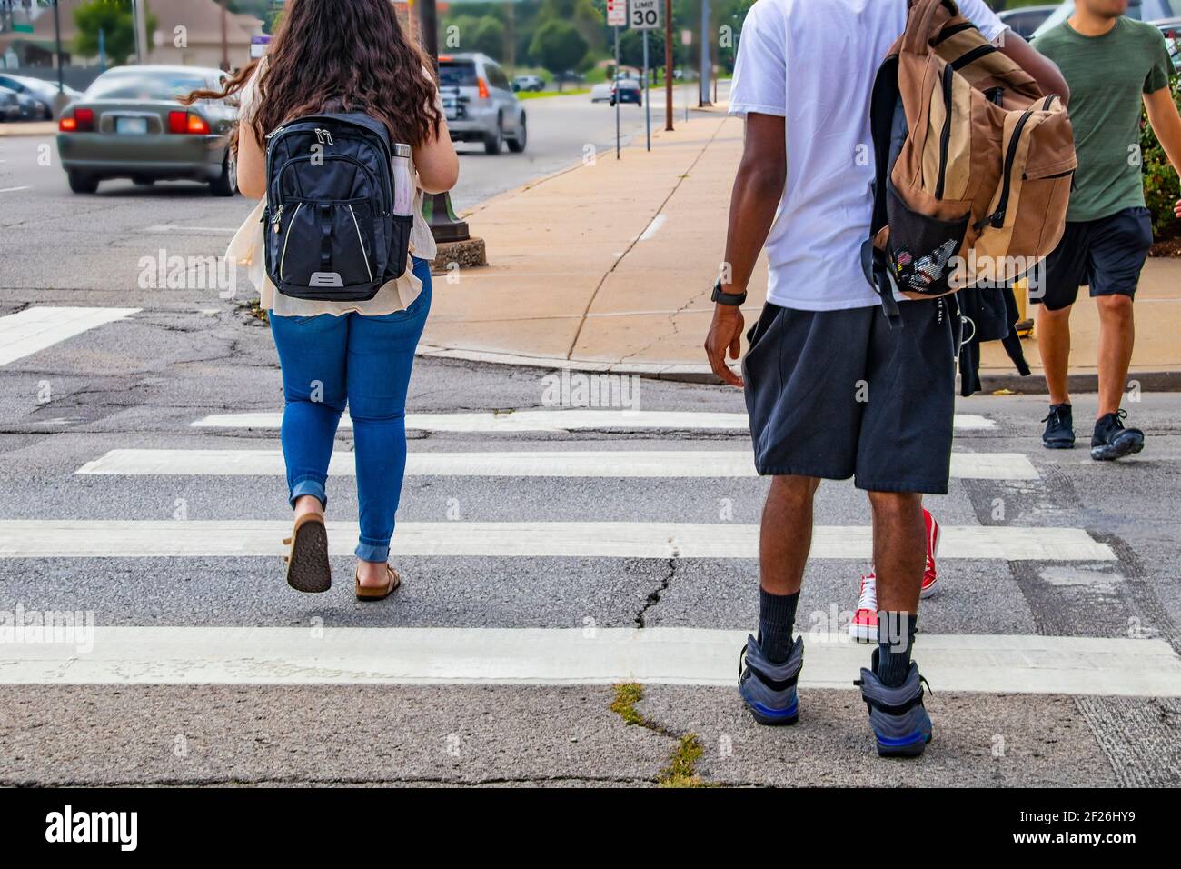 Retour à l'école - les dos des étudiants de l'université traversant tableau de concordance urbain avec sacs à dos - diversité ethnique et tenue décontractée avec des voitures en voiture Banque D'Images