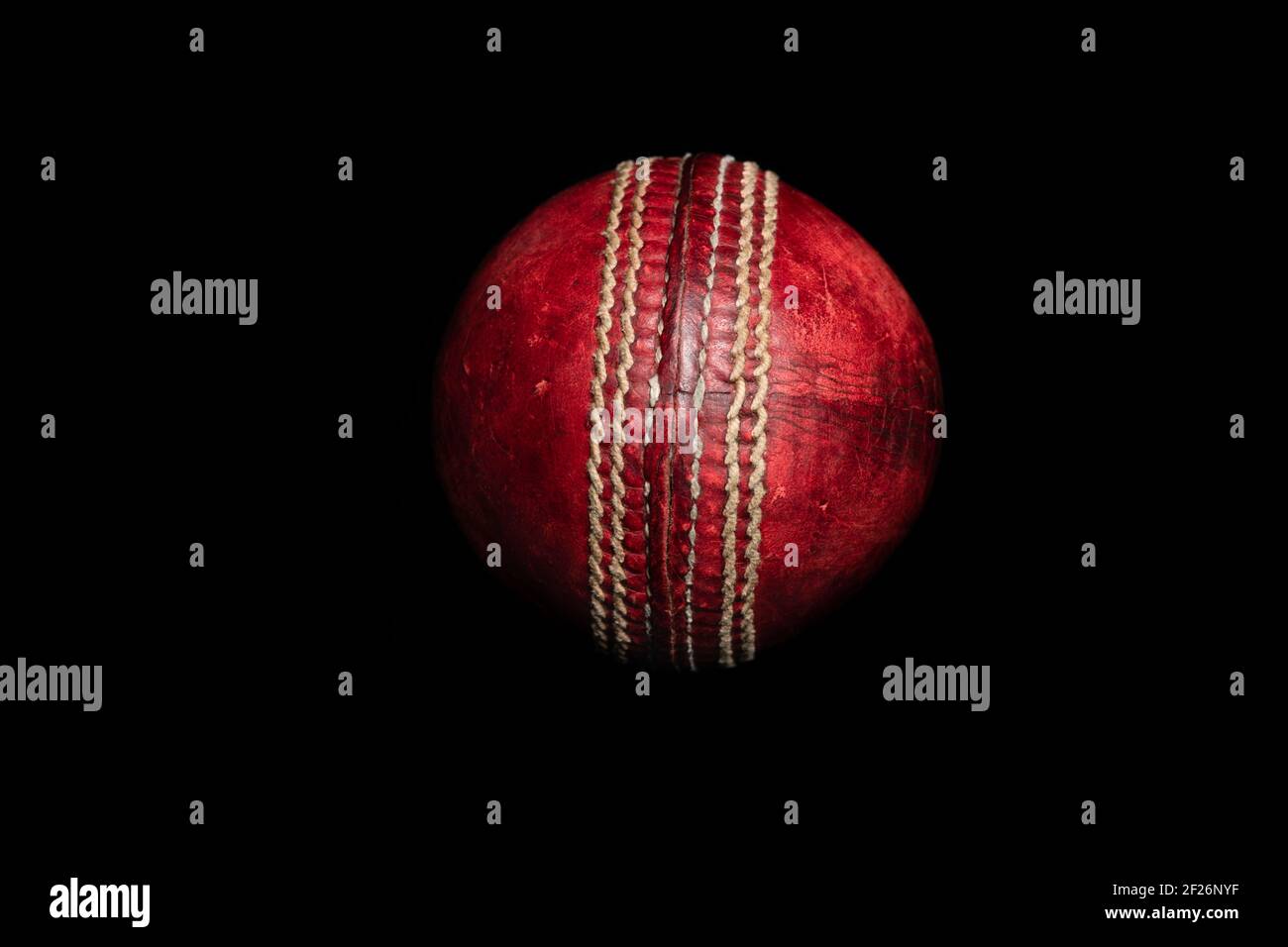 Ballon de cricket en cuir rouge sur fond noir Banque D'Images