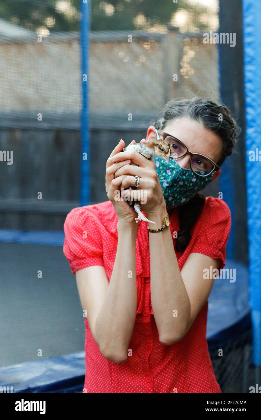 Femme tenant un poulet dans une cour urbaine Banque D'Images