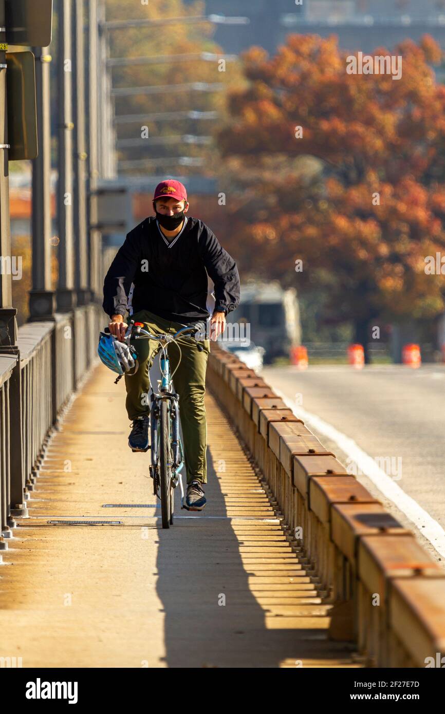 Washington DC, États-Unis 11-06-2020: Un homme se déplace pour travailler sur son vélo. Il le traverse sur le pont Theodore Roosevelt au-dessus du fleuve Potomac. Il a un narro Banque D'Images