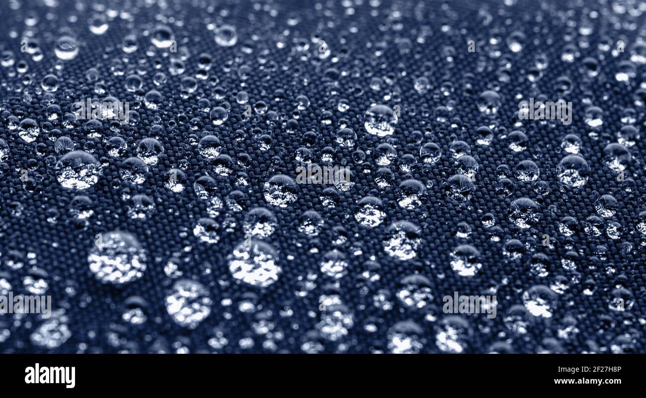 Beaucoup de gouttes d'eau sur tissu bleu foncé imperméable Banque D'Images