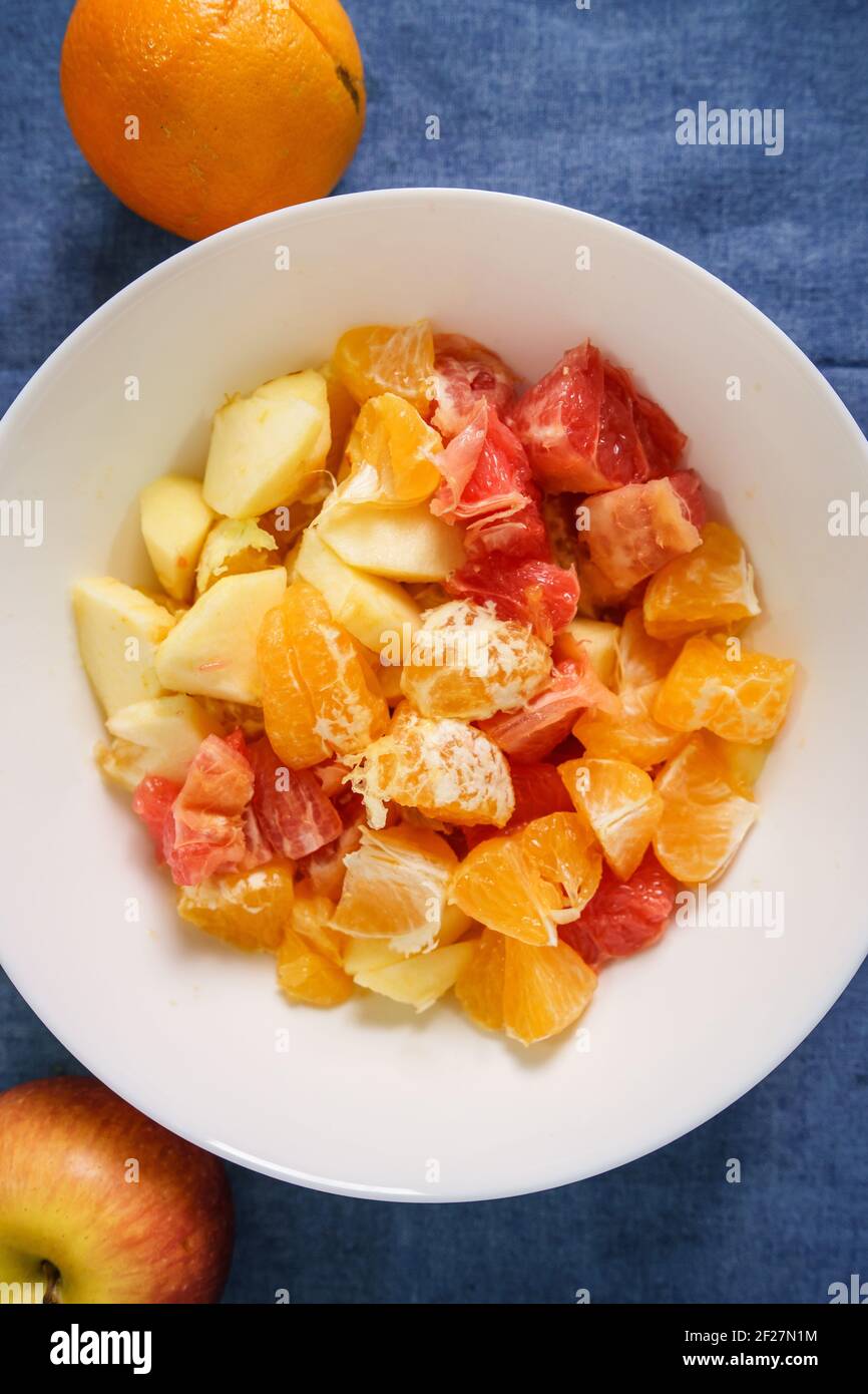 Vue de dessus de divers fruits dans le bol blanc la table à la maison - salade de fruits concept de saine alimentation plats végétariens ou végétaliens prêts à manger Banque D'Images