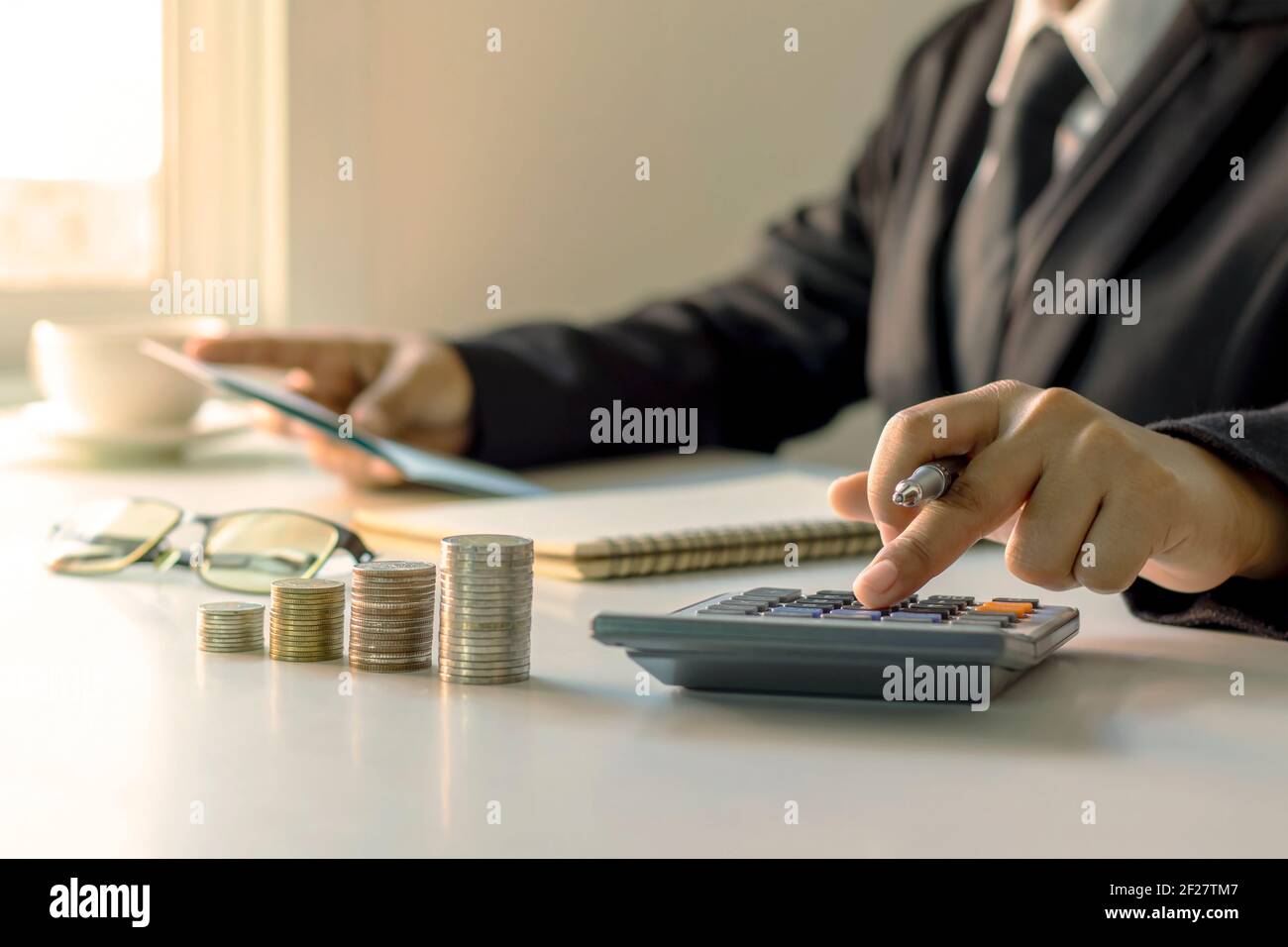L'homme d'affaires tient un stylo et appuie sur une calculatrice, des idées de planification de l'investissement et de la croissance de l'argent. Banque D'Images