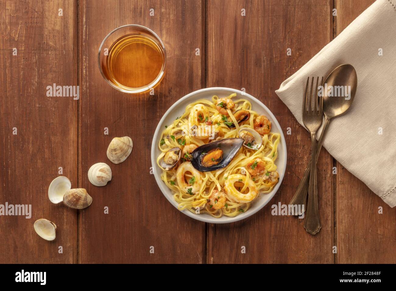 Pâtes de fruits de mer. Tagliolini aux moules, crevettes, palourdes et cernes, avec un verre de vin, des coquilles, une fourchette et une cuillère, grenaille Banque D'Images