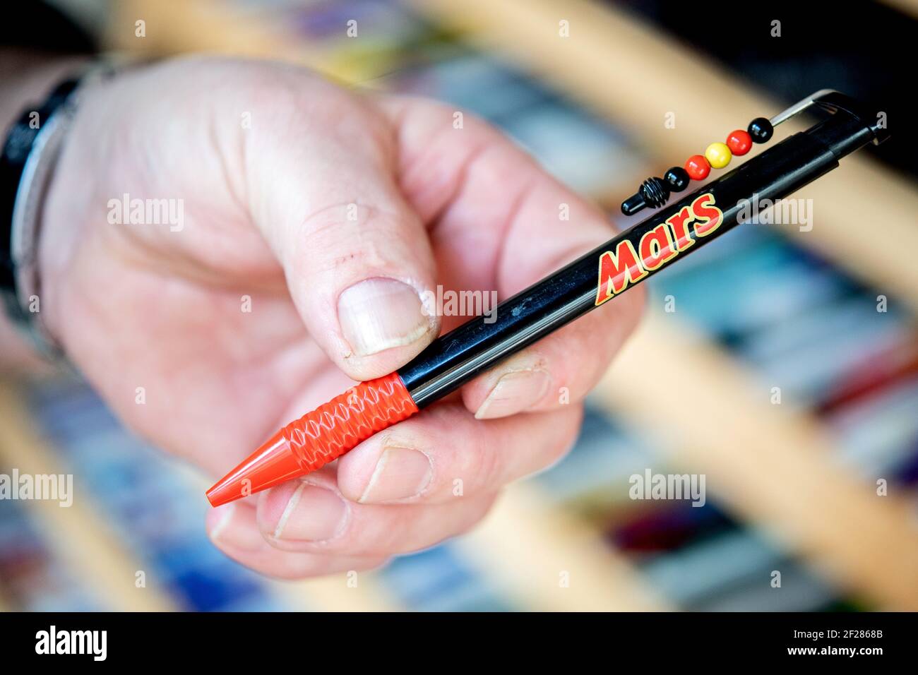 Rhauderfehn, Allemagne. 25 février 2021. Le collectionneur Gerd Reck  détient le premier article de sa collection, un stylo à bille avec le logo  de la barre de chocolat Mars. Le Frison oriental