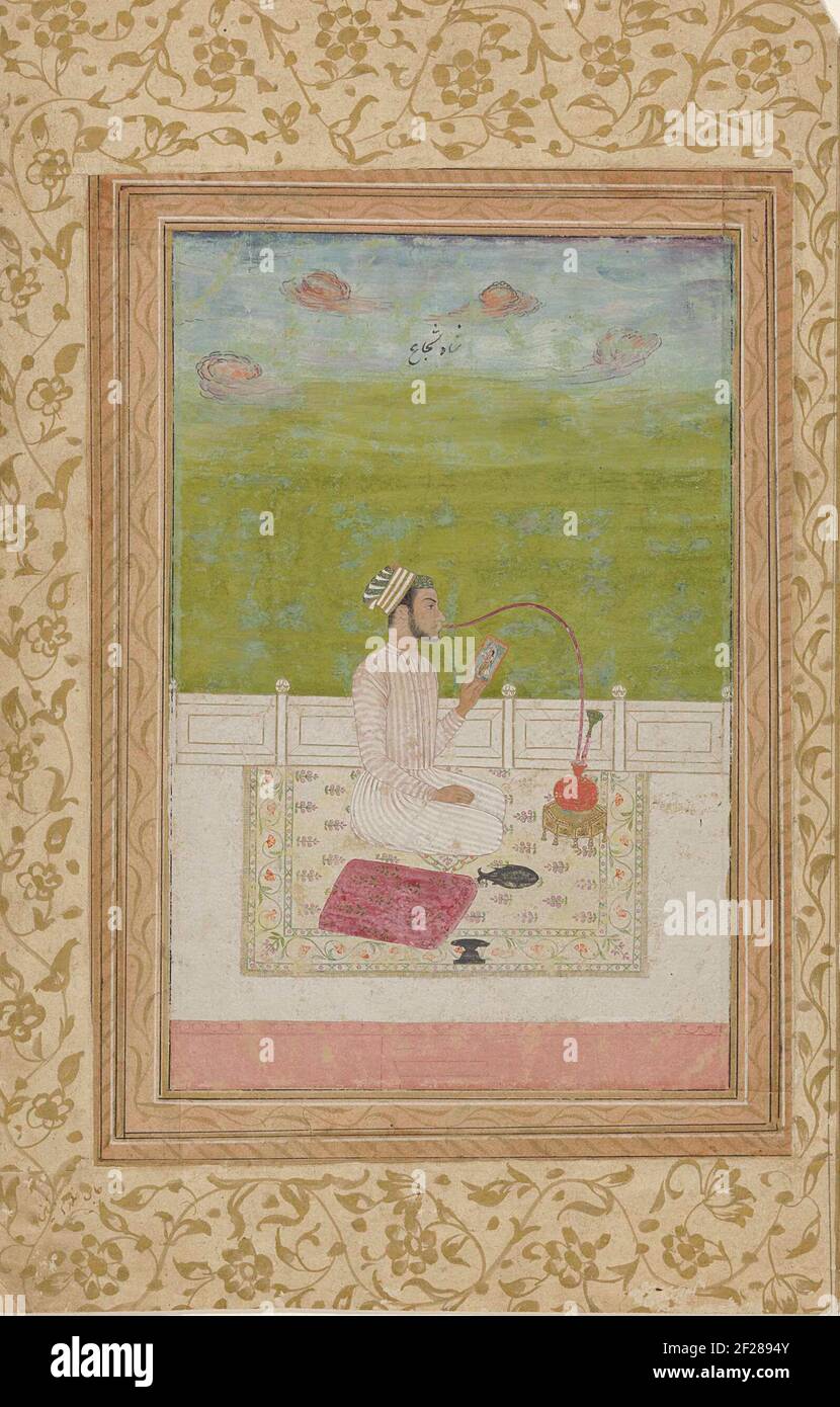 Jeune homme qui fume un tuyau d'eau assis sur une terrasse .. Banque D'Images