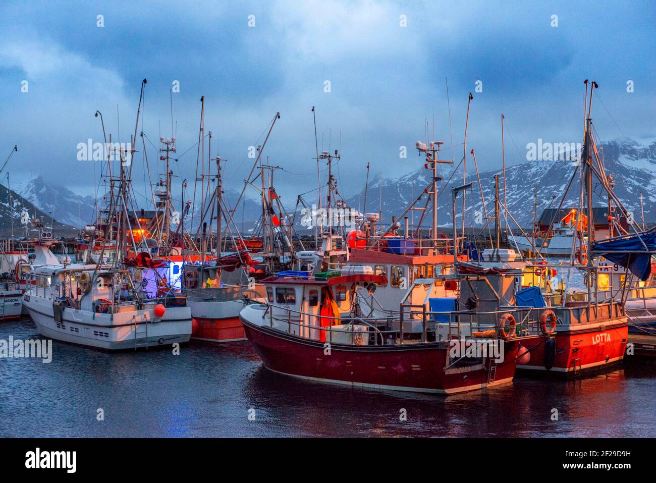 Bateaux de pêche rouges amarrés par une jetée à Reine, Moskenes, Île Moskenesøya, îles Lofoten, Norvège. Banque D'Images