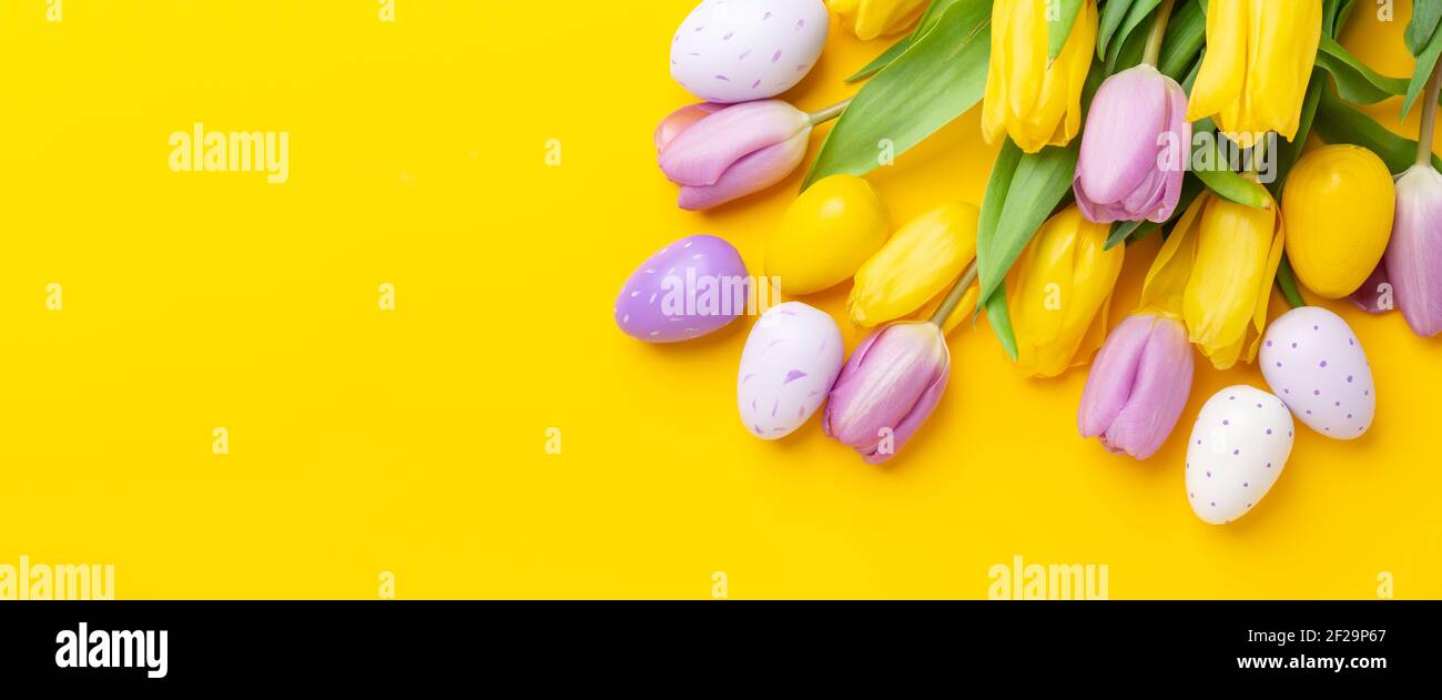 Composition de Pâques. Oeufs de pâques multicolores et tulipes sur fond jaune. Concept de Pâques. Copier l'espace. Bannière horizontale - image Banque D'Images