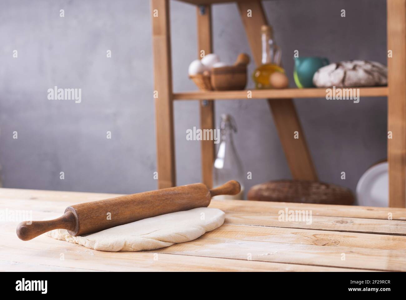 Pâte de blé à la poudre de farine et rollPIN sur la table pour la cuisson du pain maison ou la cuisson. Les aliments sont fixés sur un plan d'examen en bois près de la texture de fond du mur. B Banque D'Images