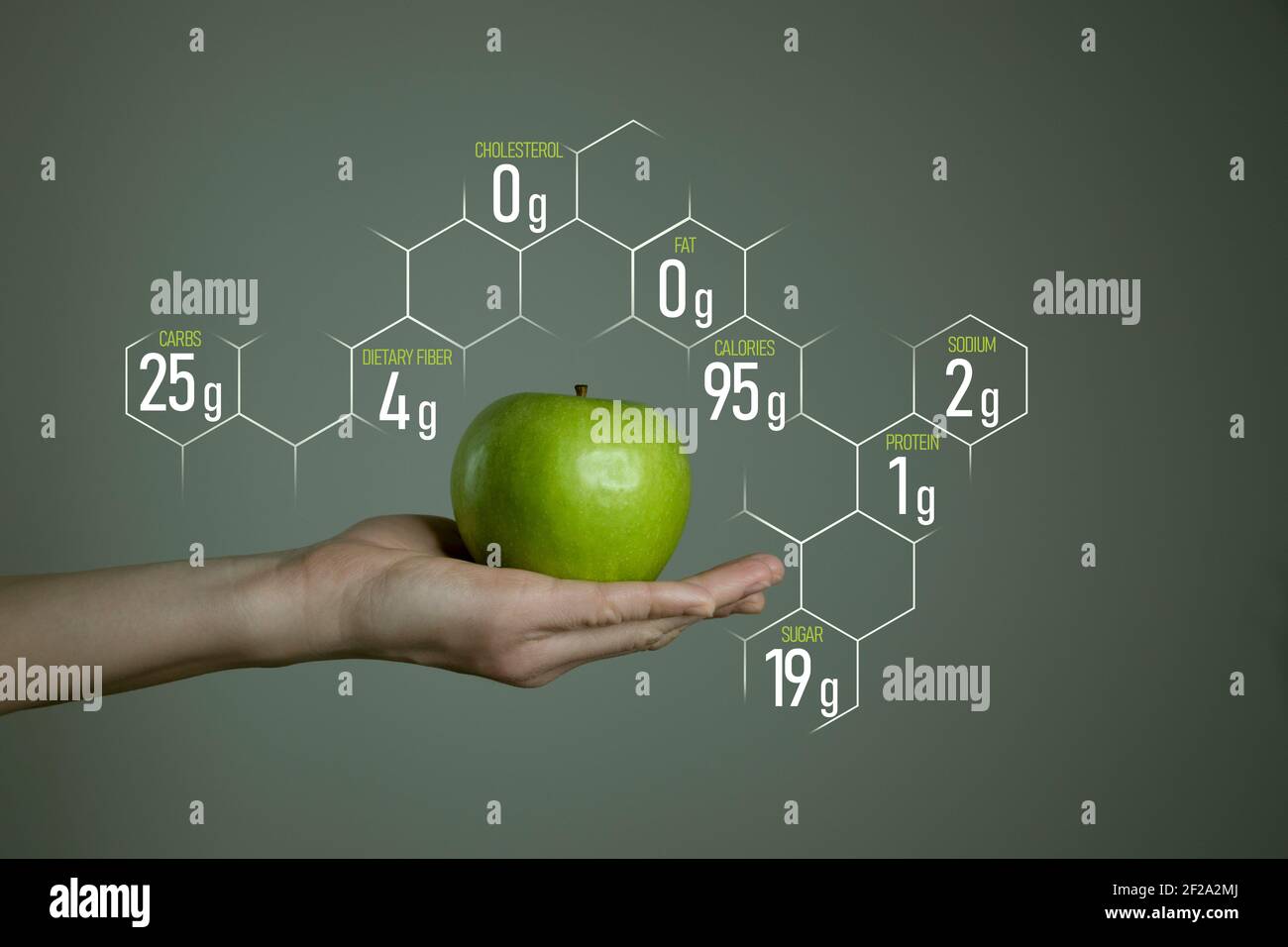 Main de femme tenant la pomme verte, faits nutritionnels sur fond gris. Modèle de concept d'aliments diététiques et de vitamines pour la publicité de produits. Banque D'Images