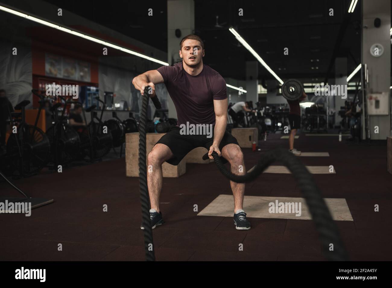Un athlète masculin fort s'entraînant avec des cordes de combat à la salle de gym, espace de copie Banque D'Images