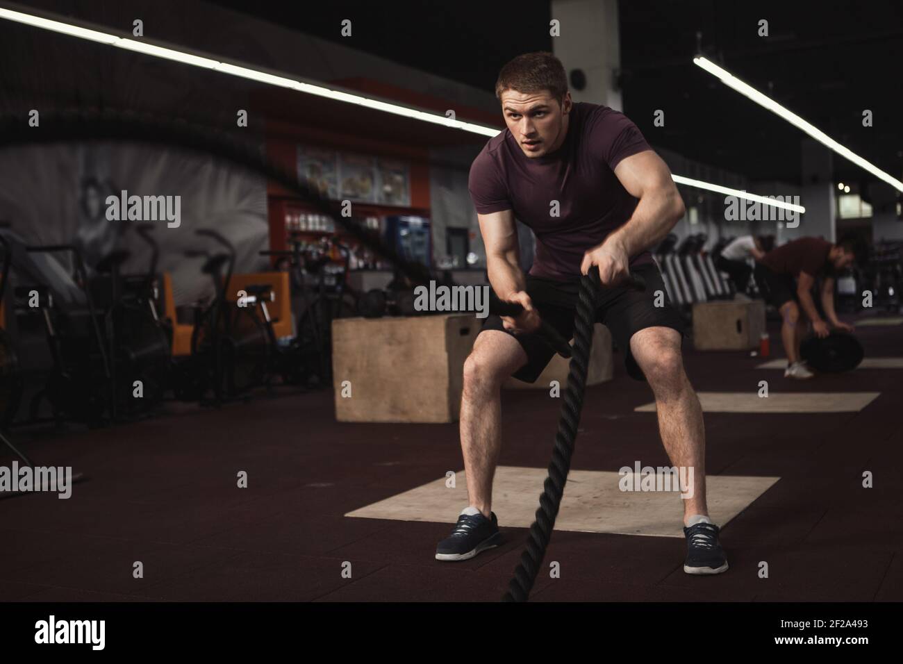 Un athlète de cross-fit qui s'y forme avec des cordes de combat salle de sport Banque D'Images