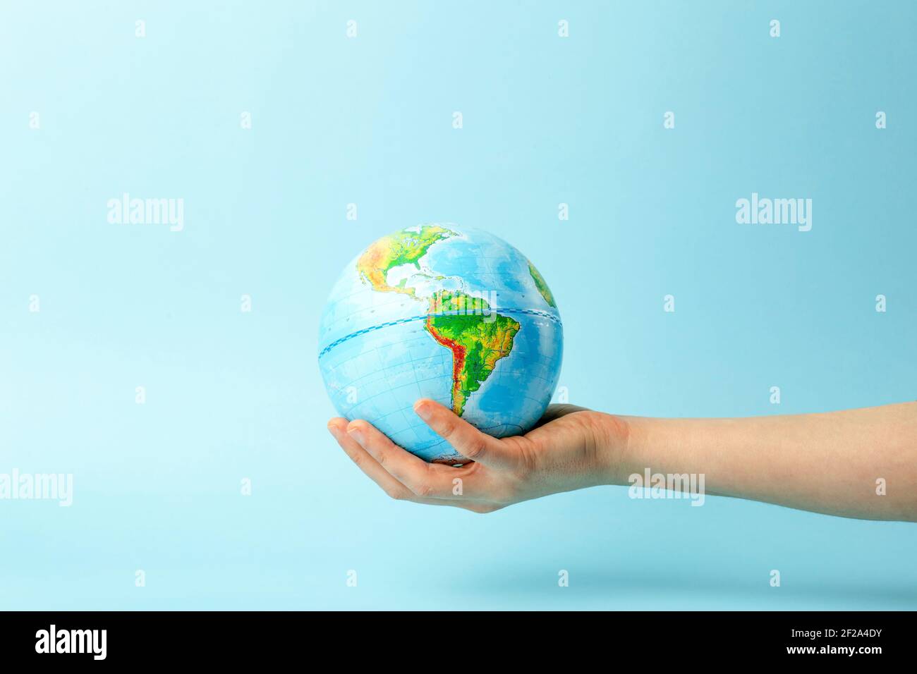 Globe terrestre dans les mains sur un fond bleu propre. Le concept de protection de la nature, de l'écologie et de la paix mondiale. Photo de haute qualité Banque D'Images