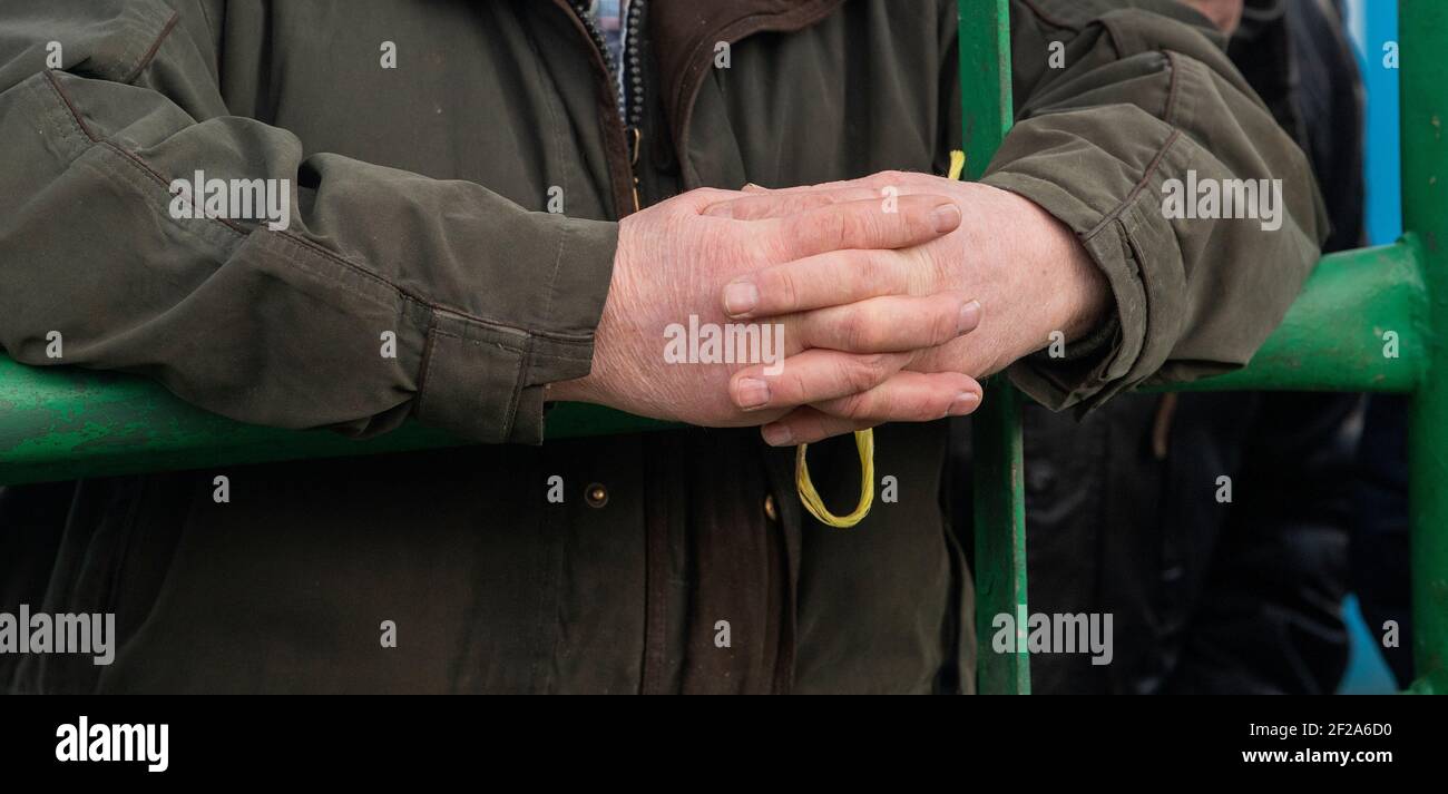 Les agriculteurs mains comme il s'appuie sur une porte à un magasin de vente aux enchères. Cumbria, Royaume-Uni. Banque D'Images