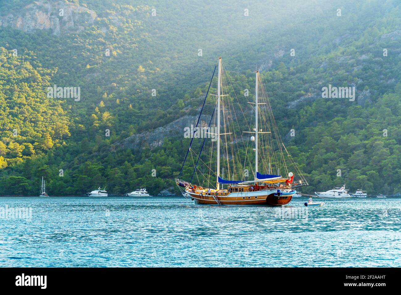 Concept d'été : un yacht turc de gullet ancré à la mer Égée avec un faisceau de soleil en arrière-plan. Photo naturelle avec espace de copie. Contraste vert et bleu Banque D'Images