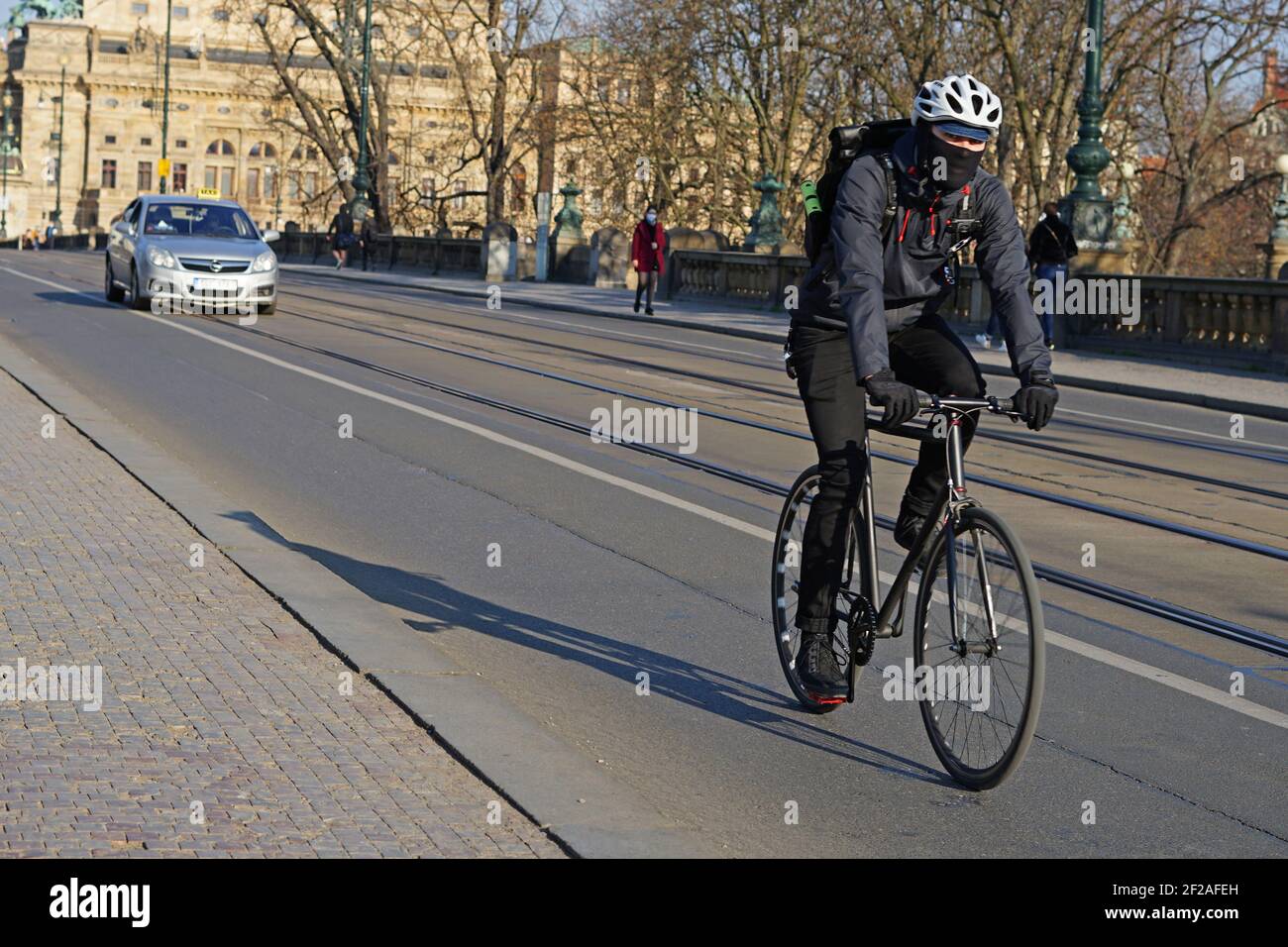 Prague, République Tchèque - avril 3 2020 : pilote de livraison de vélo avec foulard protecteur sur la route pendant l'épidémie de coronavirus Covid-19 Banque D'Images