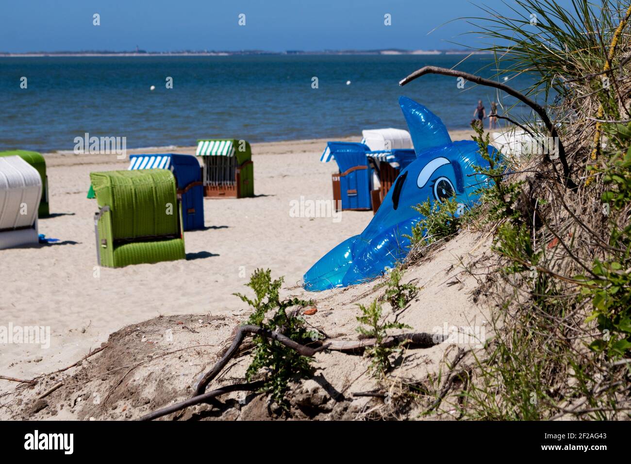 Un gros plan d'un dauphin gonflable et d'un osier couvert vide chaises de plage sur une plage de sable Banque D'Images