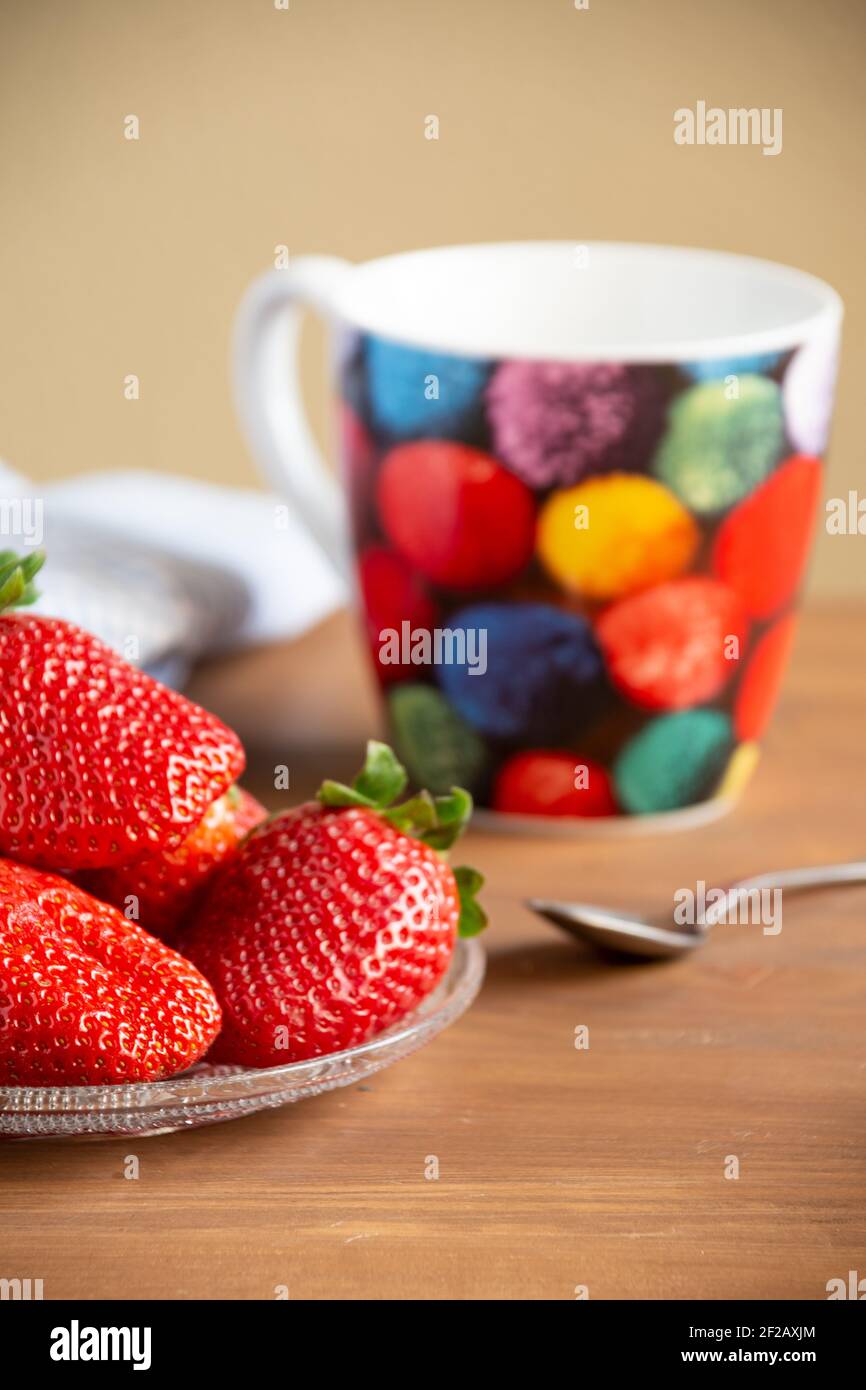 Gros plan de la plaque à fraises, tasse de couleur, cuillère et tissu, avec une mise au point sélective, sur une table en bois, en position verticale Banque D'Images