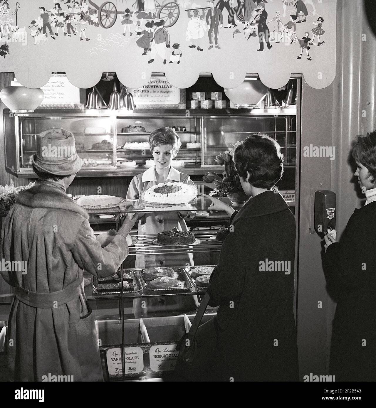 café des années 1960. Deux femmes sont debout devant le comptoir qui est plein de gâteaux et de pâtisseries fraîchement sortis du four. Suède années 1960 réf. CX81-10 Banque D'Images
