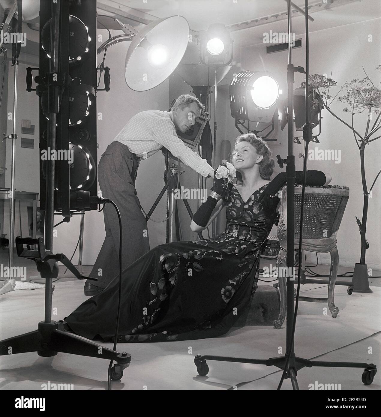 photographe et mannequin de mode des années 1940. Une jeune femme modèle est dans un studio de photographes reçoit quelques instructions finales avant de prendre les photos. Les lampes et la caméra sont visibles. Suède 1949 réf. AT7-8 Banque D'Images
