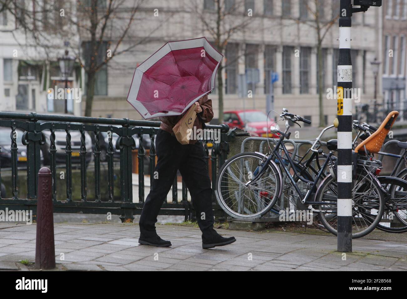 Amsterdam, pays-Bas. 11 mars 2021. Un homme tente de tenir son parapluie pendant la tempête le 11 mars 2021 à Amsterdam, pays-Bas. L'Institut néerlandais de MeteorologyÊ KNMI a émis un avertissement météorologique jaune pour theÊnationwideÊwith les vents forts et les rafales toÊwinds jusqu'à des vitesses de 80 à 100 km/h. (Photo de Paulo Amorim/Sipa USA) Credit: SIPA USA/Alay Live News Banque D'Images