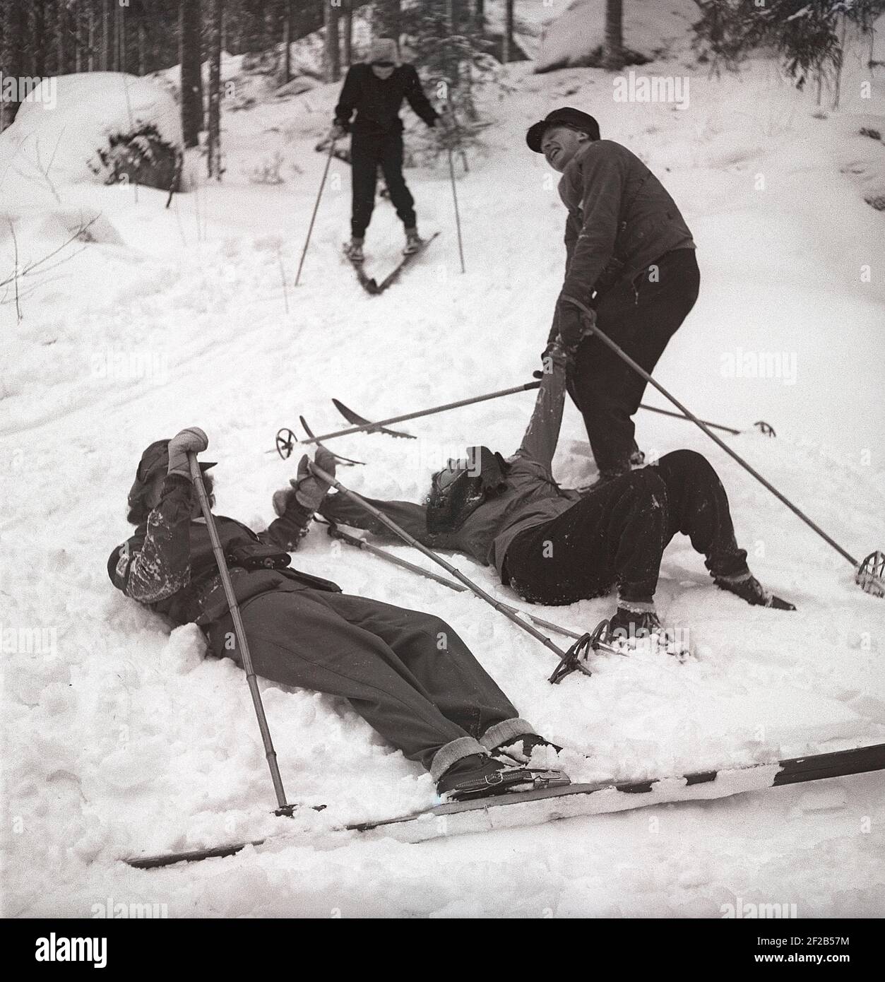 Hiver dans les années 1940. Un groupe de personnes skier et ils ont de la difficulté à se tenir directement dessus. Un homme essaie de donner une main d'aide pour se remettre debout. Suède 1947. Kristoffersson Réf. AA30-9 Banque D'Images