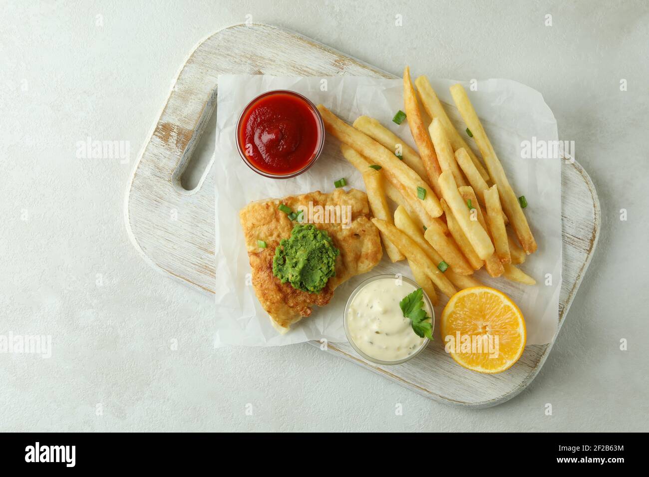 Concept de manger savoureux avec du poisson frit et des frites arrière-plan texturé blanc Banque D'Images