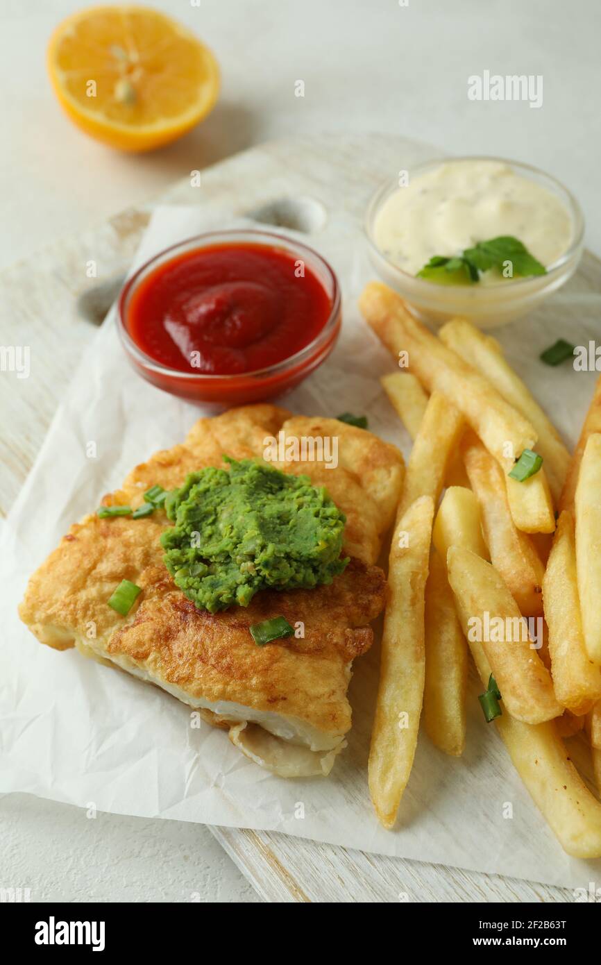 Concept de manger savoureux avec du poisson frit et des frites table texturée blanche Banque D'Images