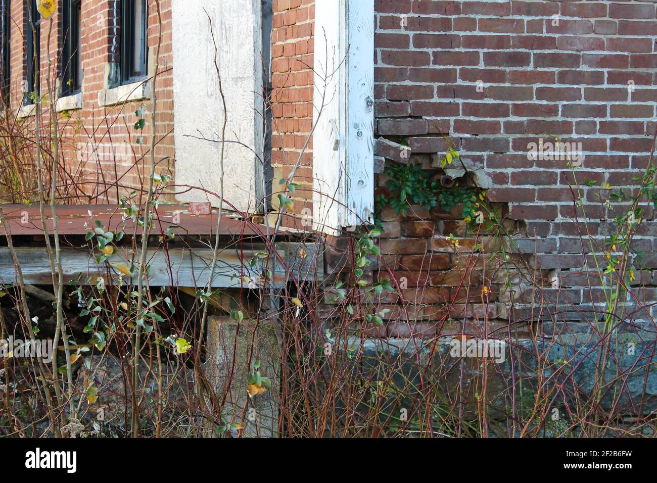 Gros plan d'un mur de briques endommagé dans un ancien bâtiment abandonné, où la couche extérieure de briques est tombée, révélant une autre couche de briques. Banque D'Images