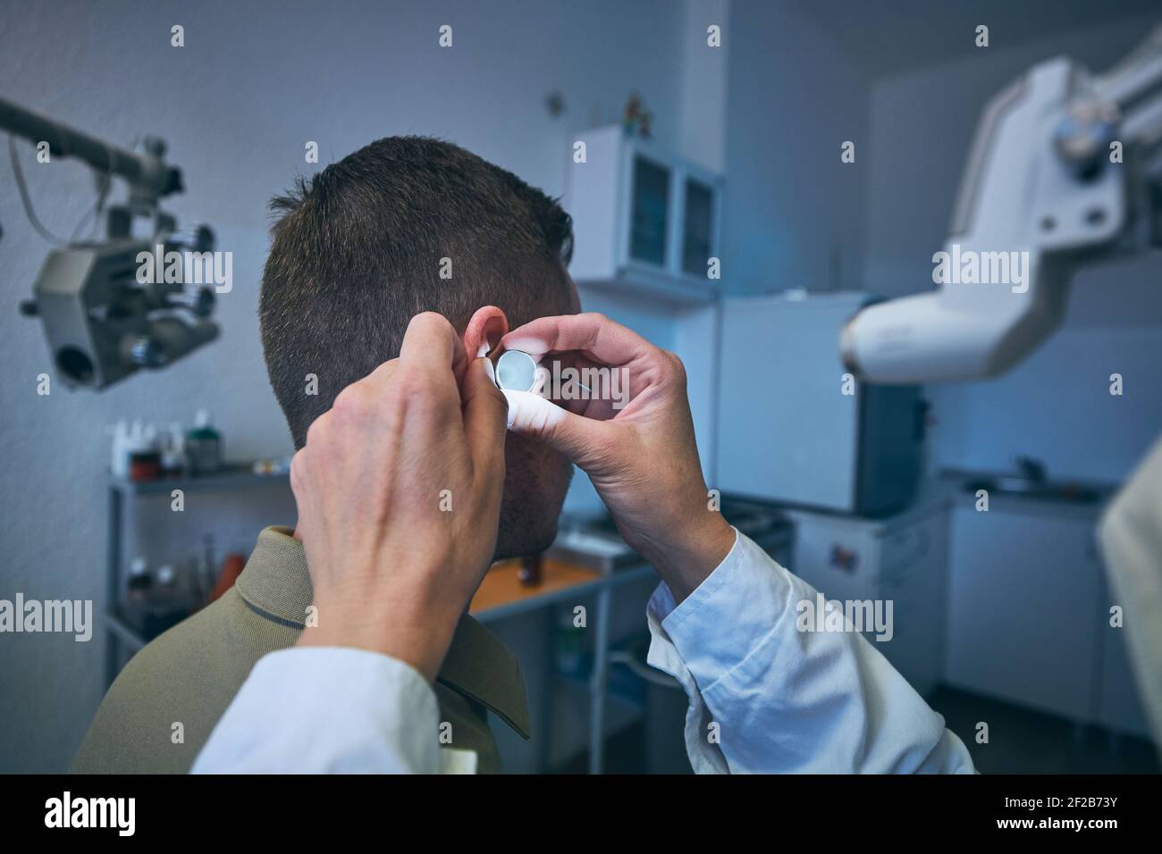 Patient à la clinique ORL. Médecin spécialiste - Otolaryngologiste effectuant un examen de l'oreille d'un jeune homme. Banque D'Images