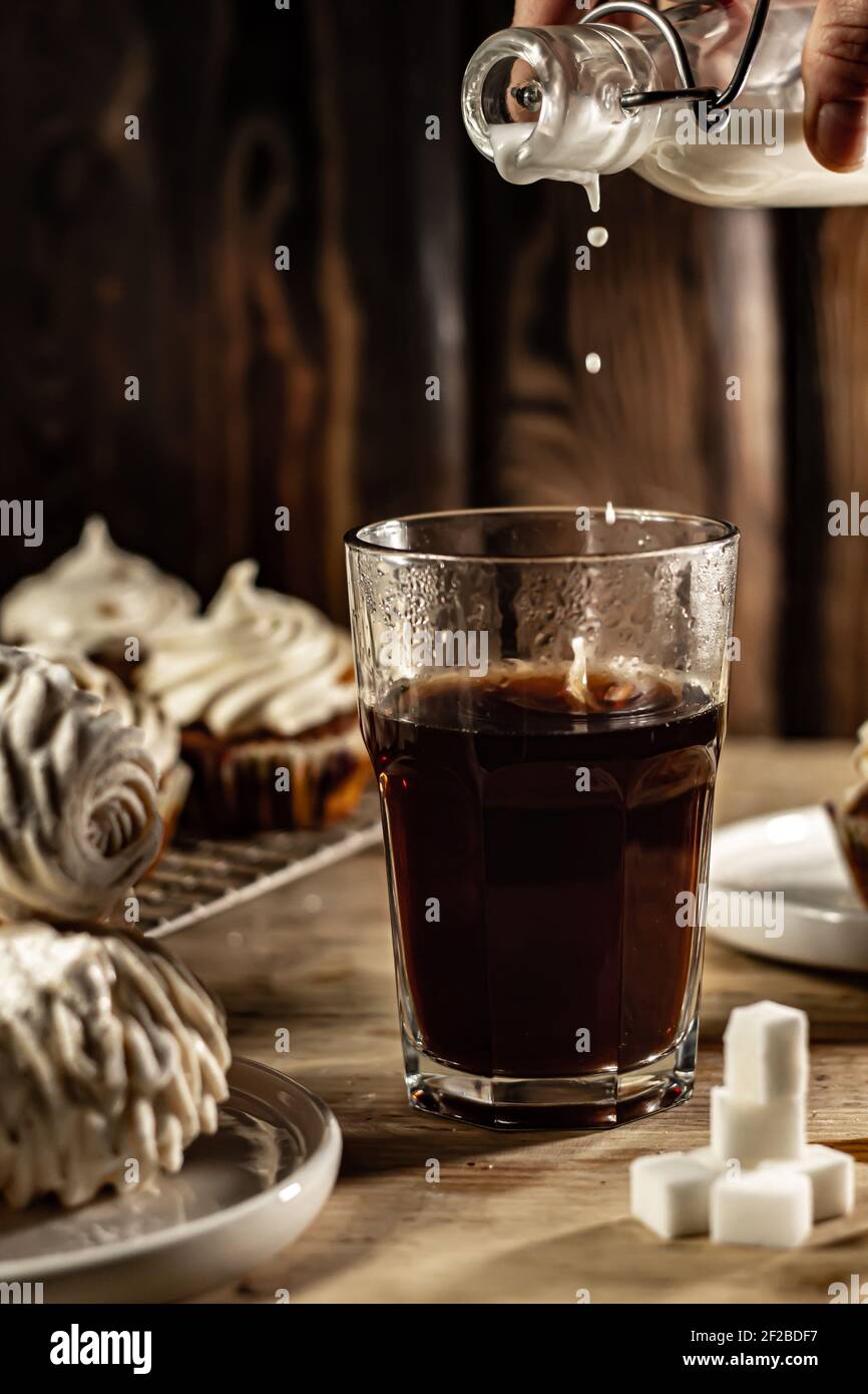 Verser le lait dans un verre de café chaud. Banque D'Images