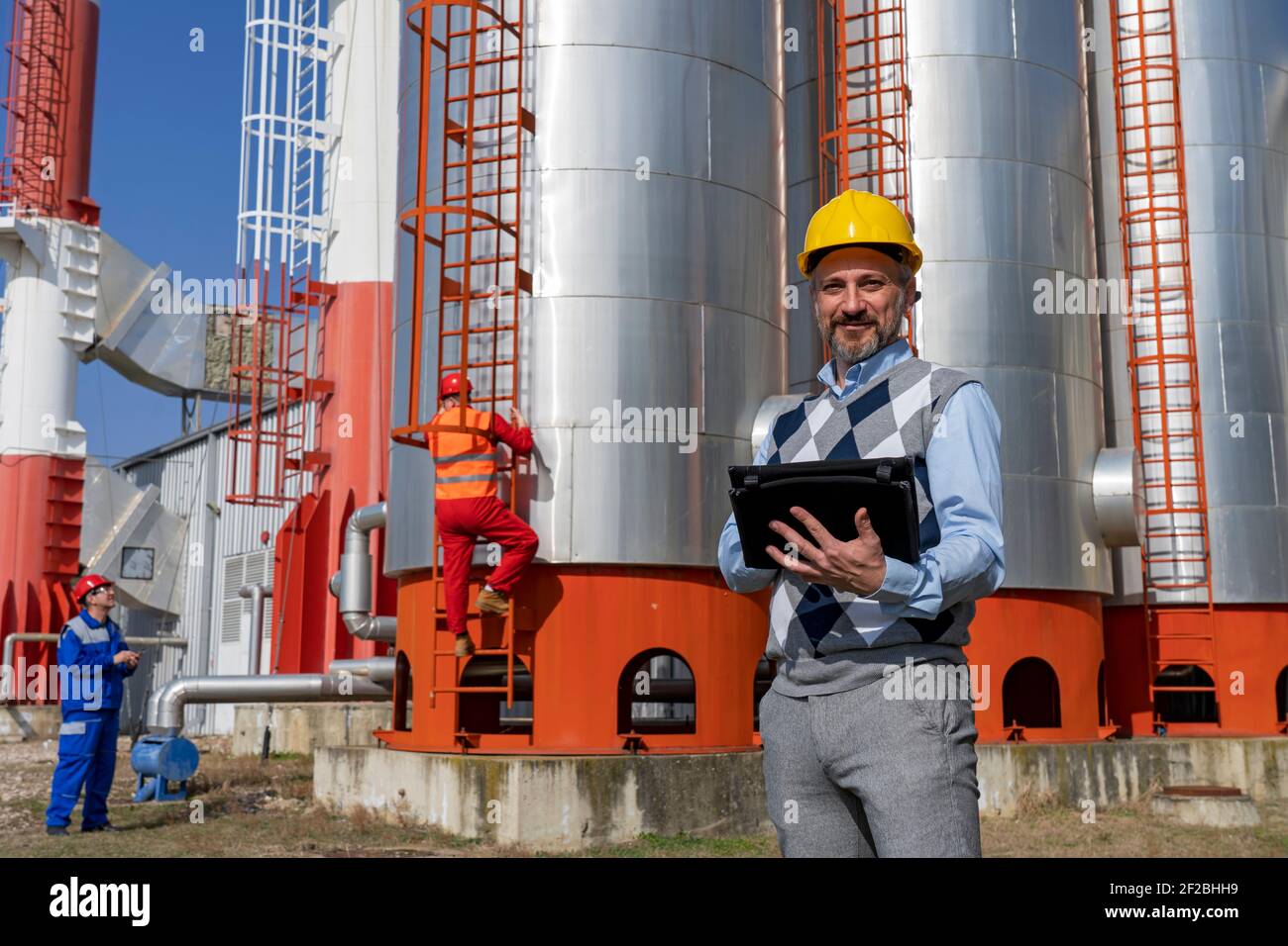 Portrait d'une personne d'affaires avec deux travailleurs en équipement de protection individuelle aux travaux d'entretien dans la centrale électrique de chauffage de district. Concept de travail d'équipe. Banque D'Images
