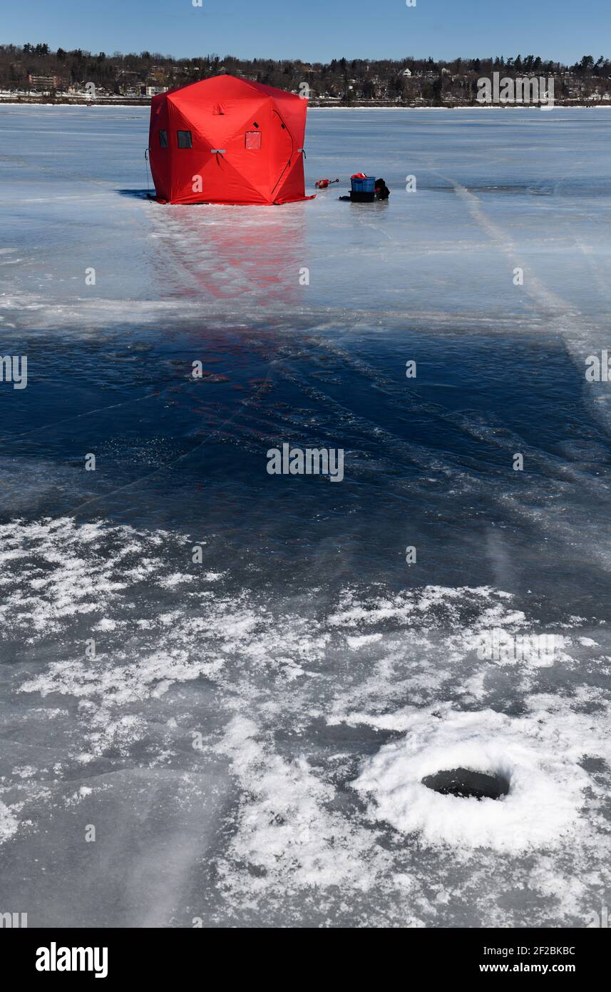 Tente de pêche sous la glace rouge avec ancien trou de glace sur la glace congelée Glace bleue de la baie de Kempenfelt sur le lac Simcoe en hiver Banque D'Images