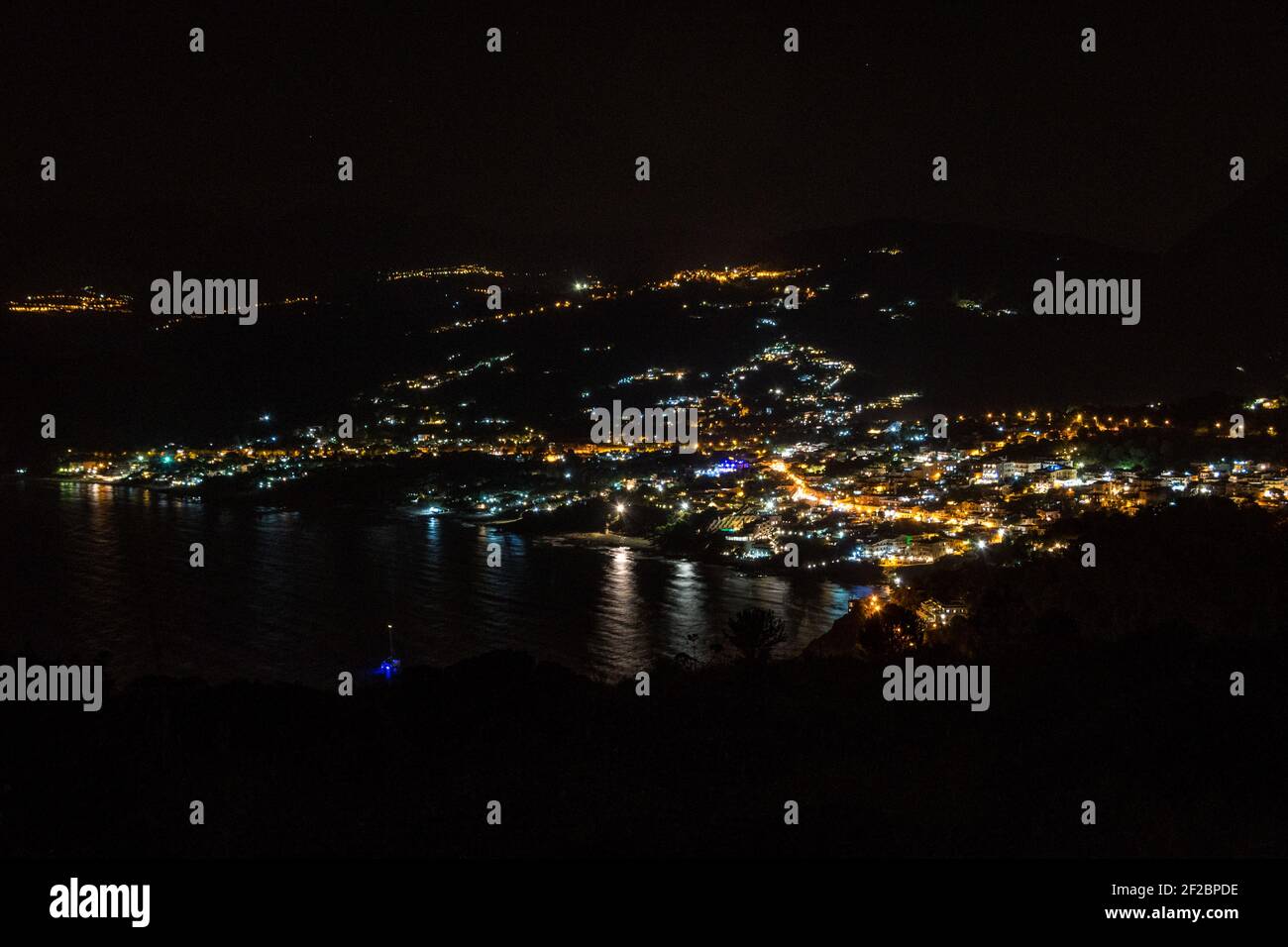 La ville de Palinuro de nuit en face de la mer Tyrrhénienne du promontoire 'Capo Palinuro' avec le phare à Cilento, Campanie, Italie Banque D'Images