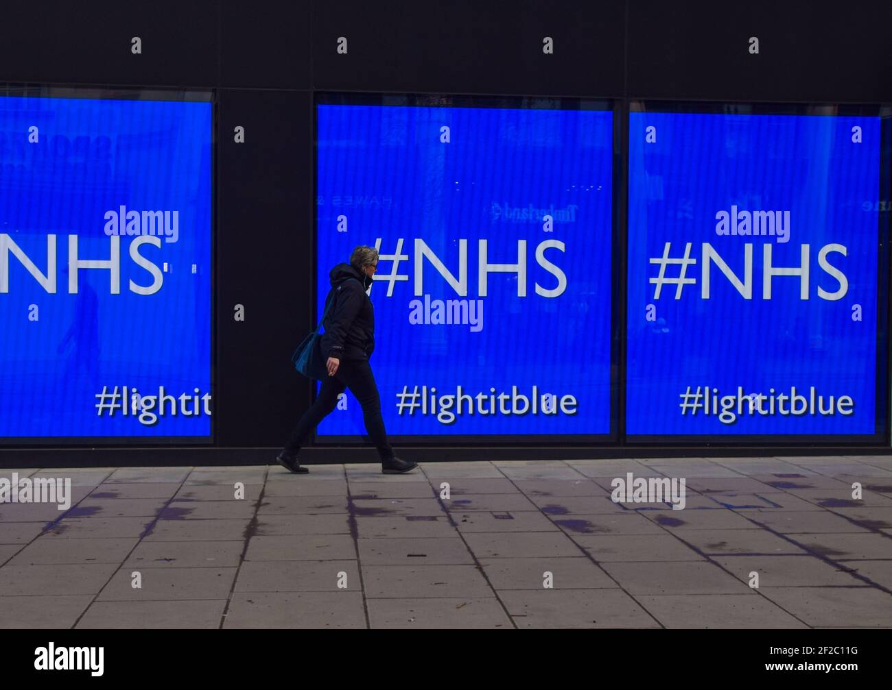 Un homme passe devant les écrans affichant « NHS » au magasin de flanelles d'Oxford Street à Londres. Les écrans du magasin montraient une série d'œuvres d'art dans le cadre de la campagne « Light IT Blue » en soutien au NHS pendant la crise du coronavirus. (Photo de Vuk Valcic / SOPA Images / Sipa USA) Banque D'Images
