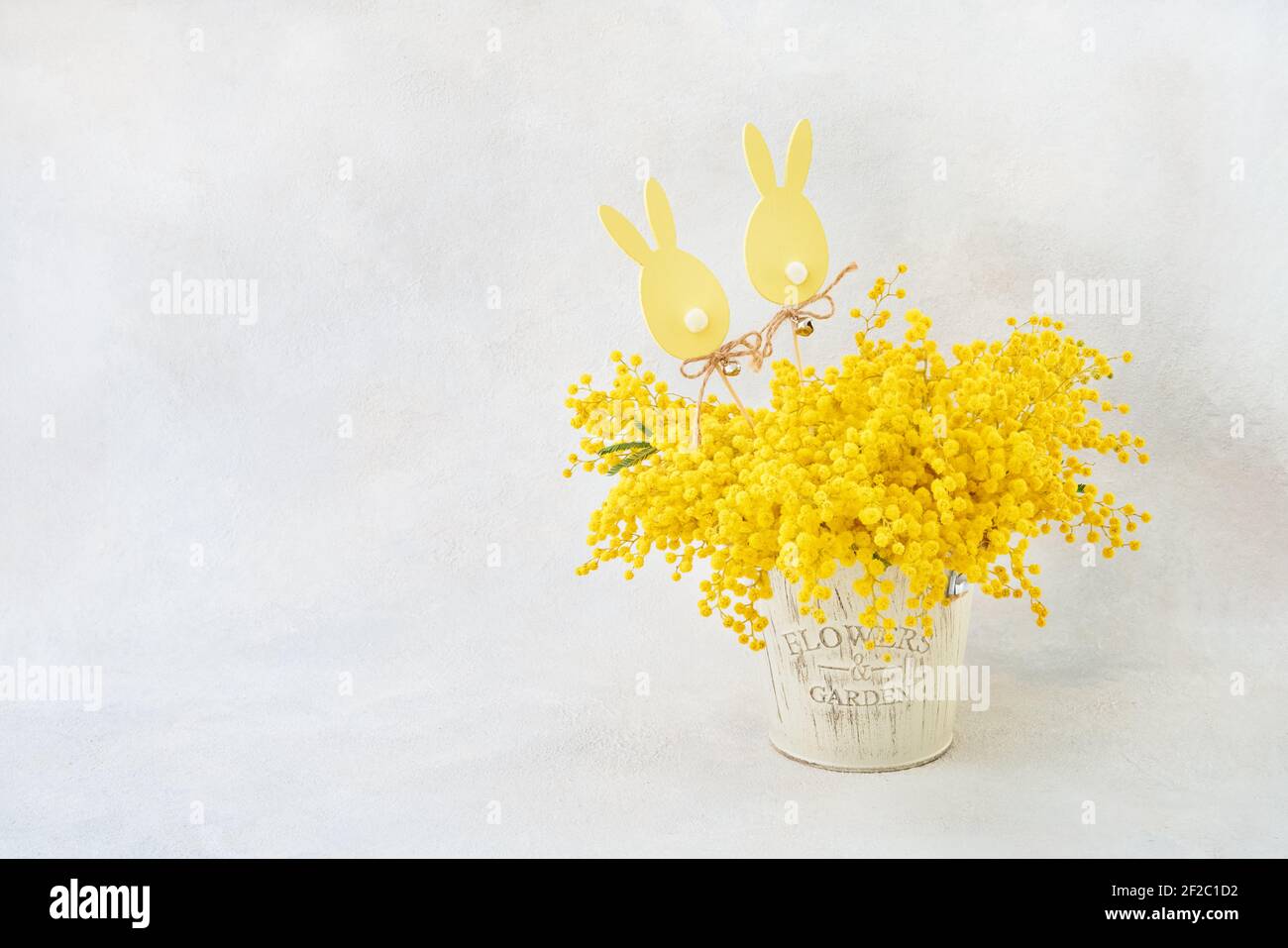 Décoration de Pâques et bouquet de fleurs Mimosa dans un vase sur fond clair. Concept de Pâques. Copier l'espace pour le texte Banque D'Images